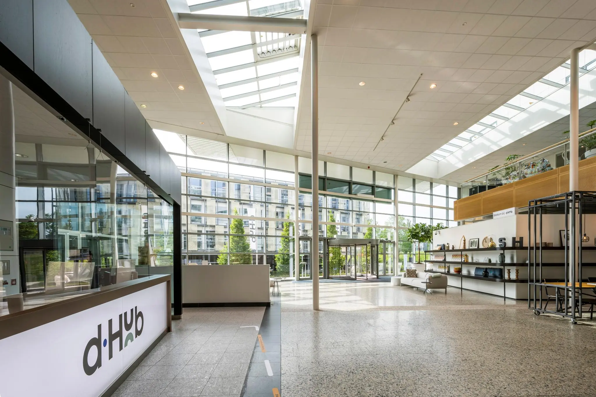 Moderne, lichtovergoten entreehal van een kantoor aan de Capellalaan met ontvangstbalie en open zithoek.