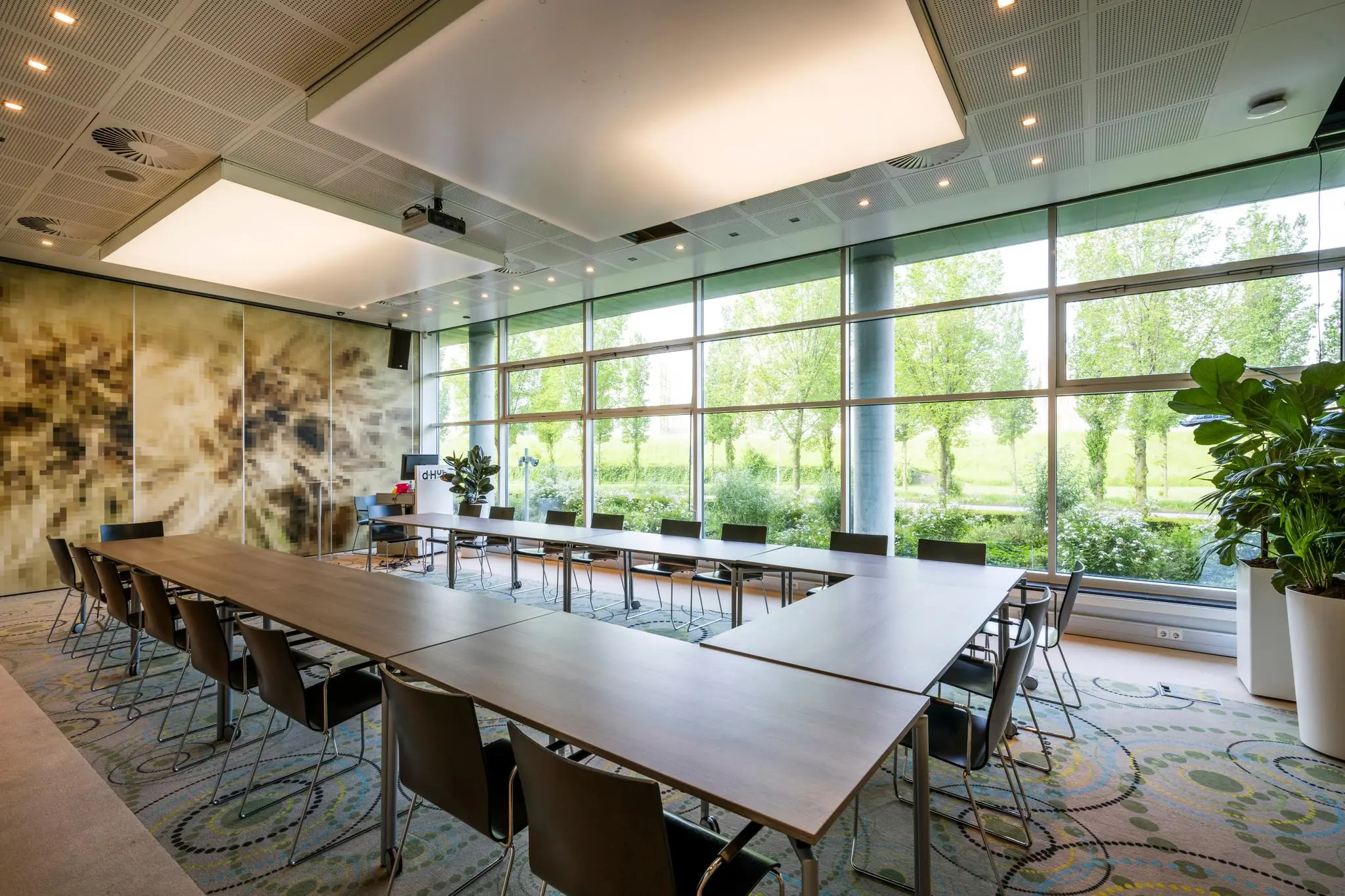 Moderne vergaderruimte aan de Capellalaan met U-opstelling, grote ramen en uitzicht op groen.