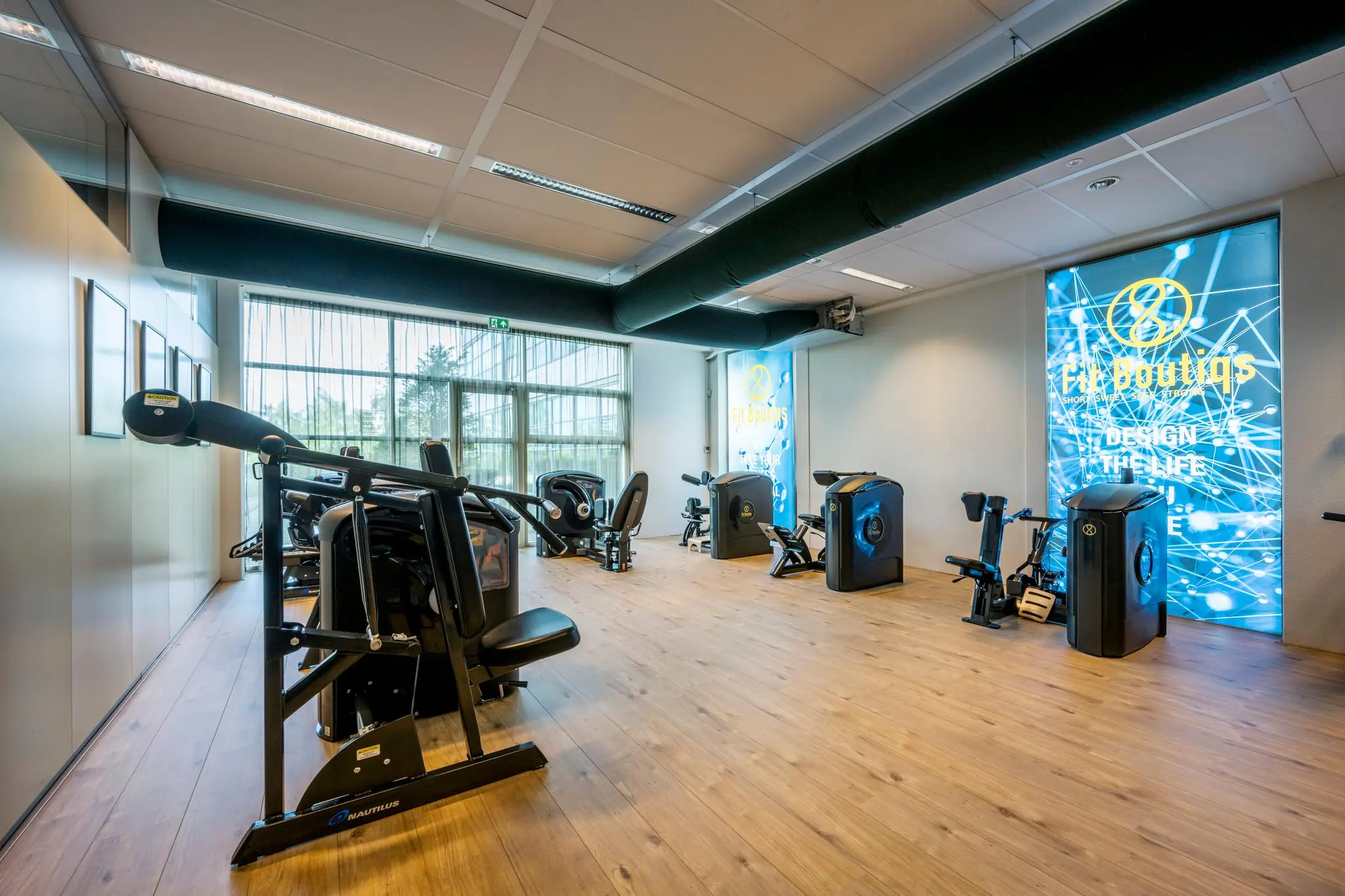 Moderne fitnessruimte aan de Capellalaan met diverse krachttrainingsapparaten en een groot raam voor natuurlijk licht.
