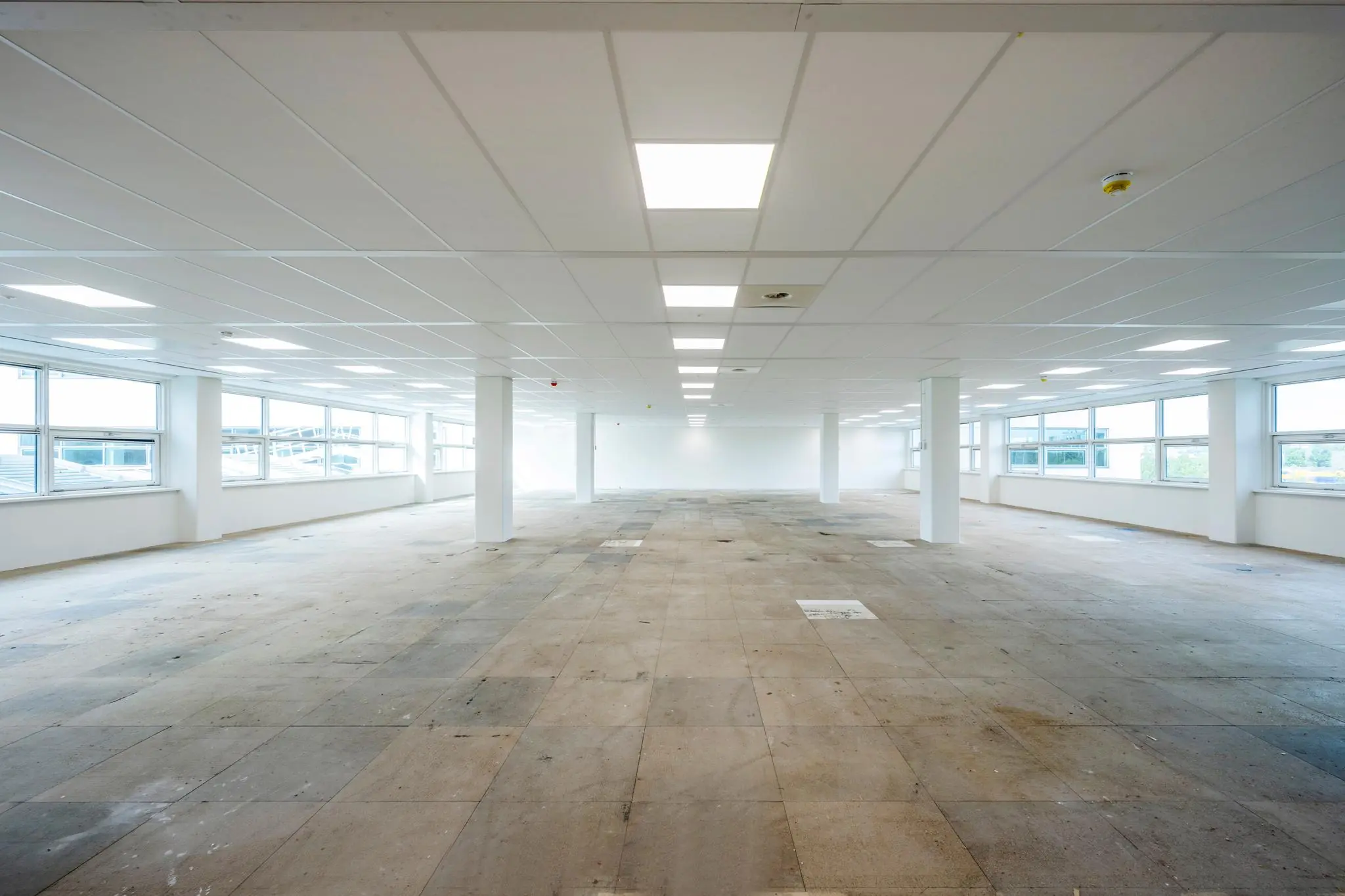 Leegstaand kantoorruimte aan de Capellalaan met systeemplafond, grote ramen en betonnen vloer.