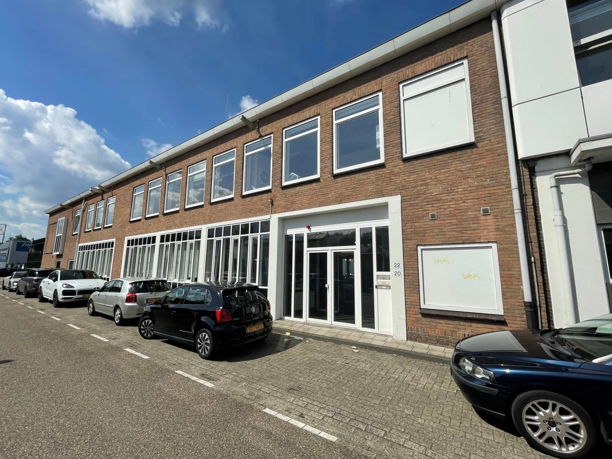 Vooraanzicht van een kantoorpand aan de Pilotenstraat met geparkeerde auto's langs de stoep.