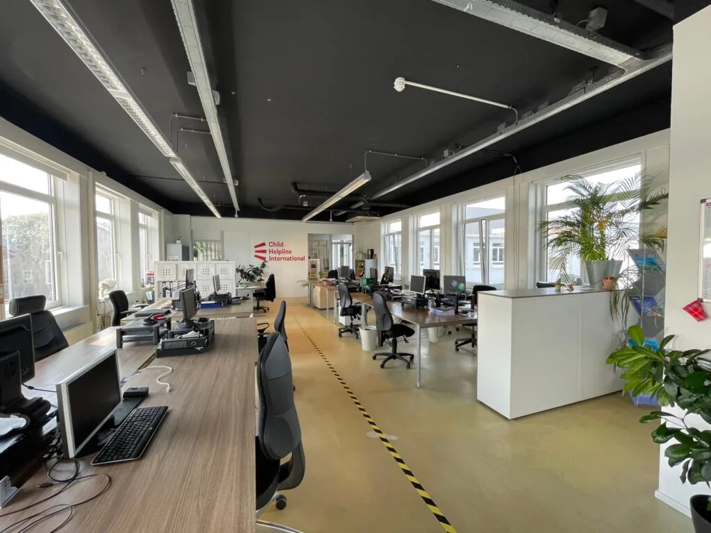 Modern kantoorinterieur van Child Helpline International aan de Pilotenstraat met werkplekken en grote ramen.