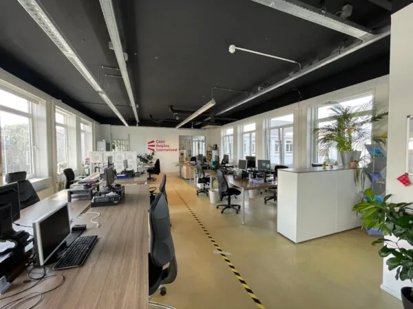 Modern kantoorinterieur van Child Helpline International aan de Pilotenstraat met werkplekken en grote ramen.