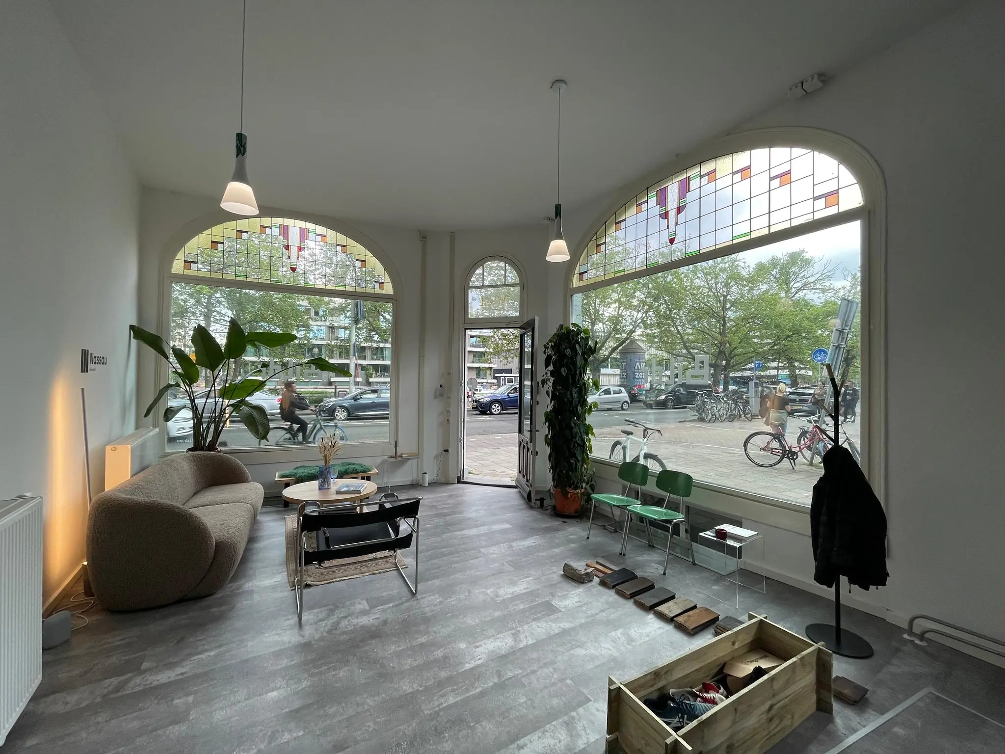 Lichte en modern ingerichte ruimte aan de Nassaukade met grote ramen, houten vloerstaaltjes en uitzicht op een drukke straat met fietsen en auto's.