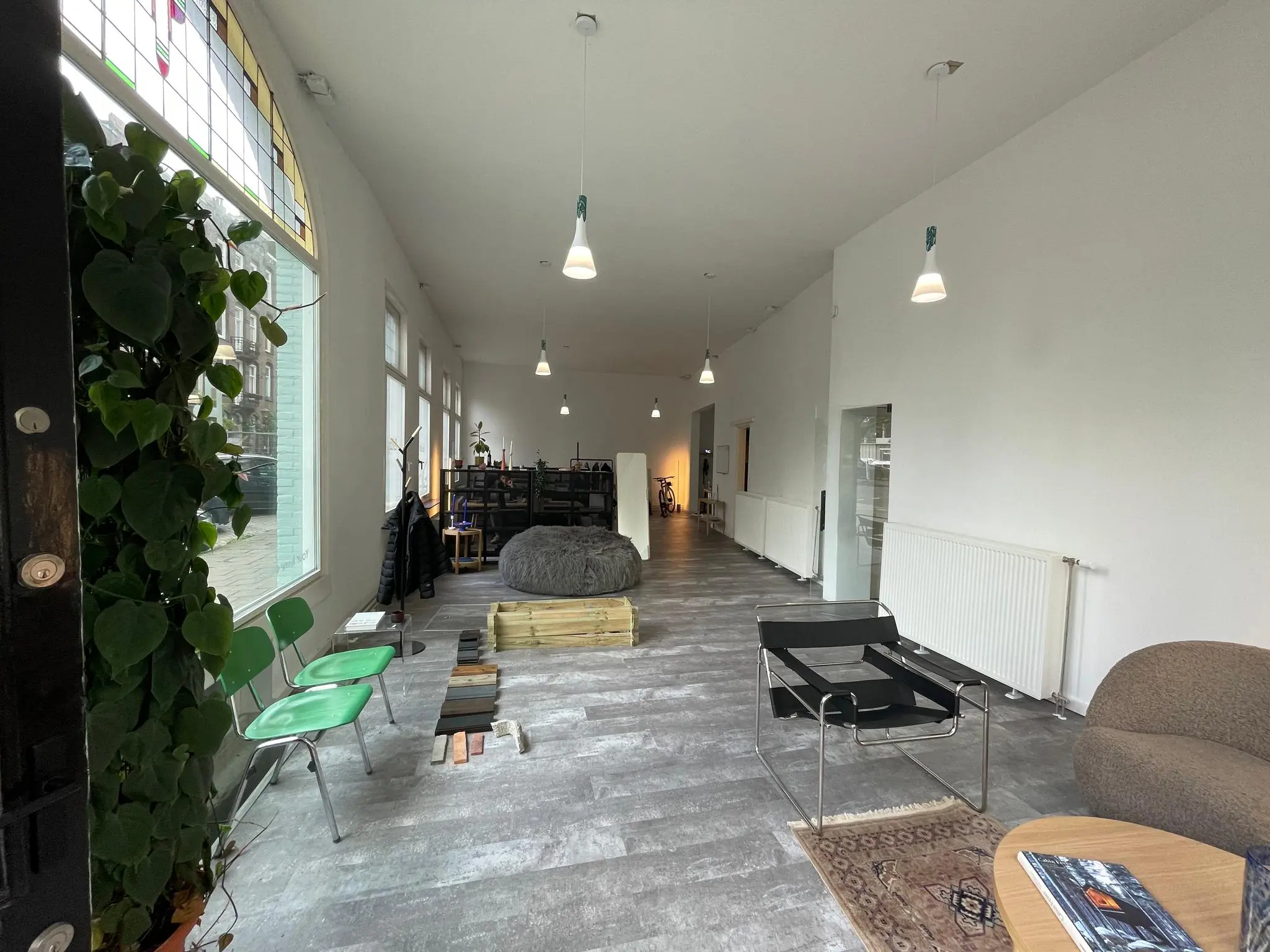 Moderne, licht ingerichte wachtruimte aan de Nassaukade met designmeubels, planten en grote ramen.