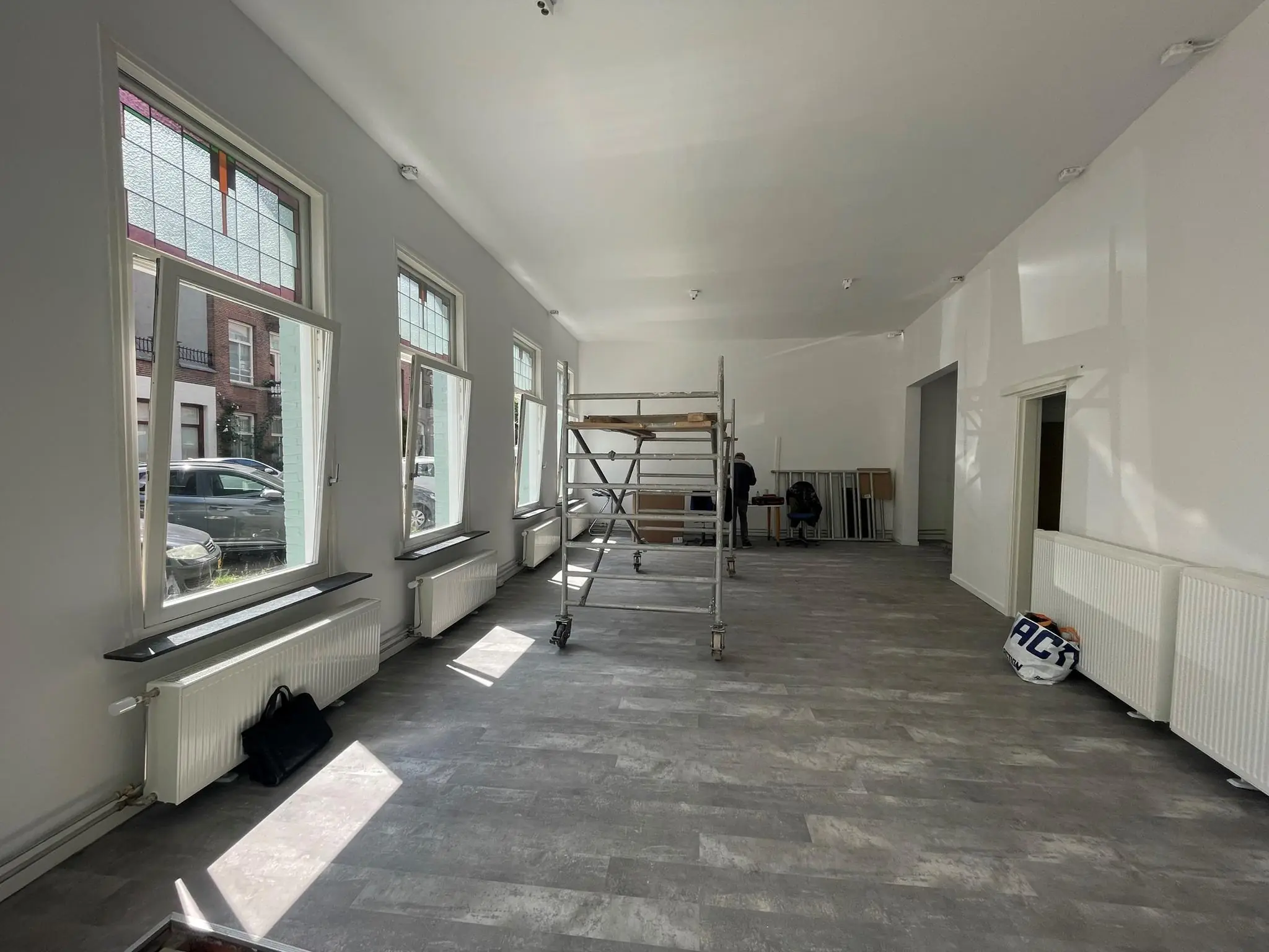 Lichte, pas gerenoveerde ruimte aan de Nassaukade met grote ramen, steiger en werkmaterialen.