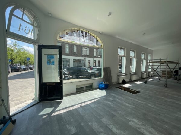 Een lichte ruimte aan de Nassaukade met grote ramen, een openstaande deur en een vloer in aanbouw.