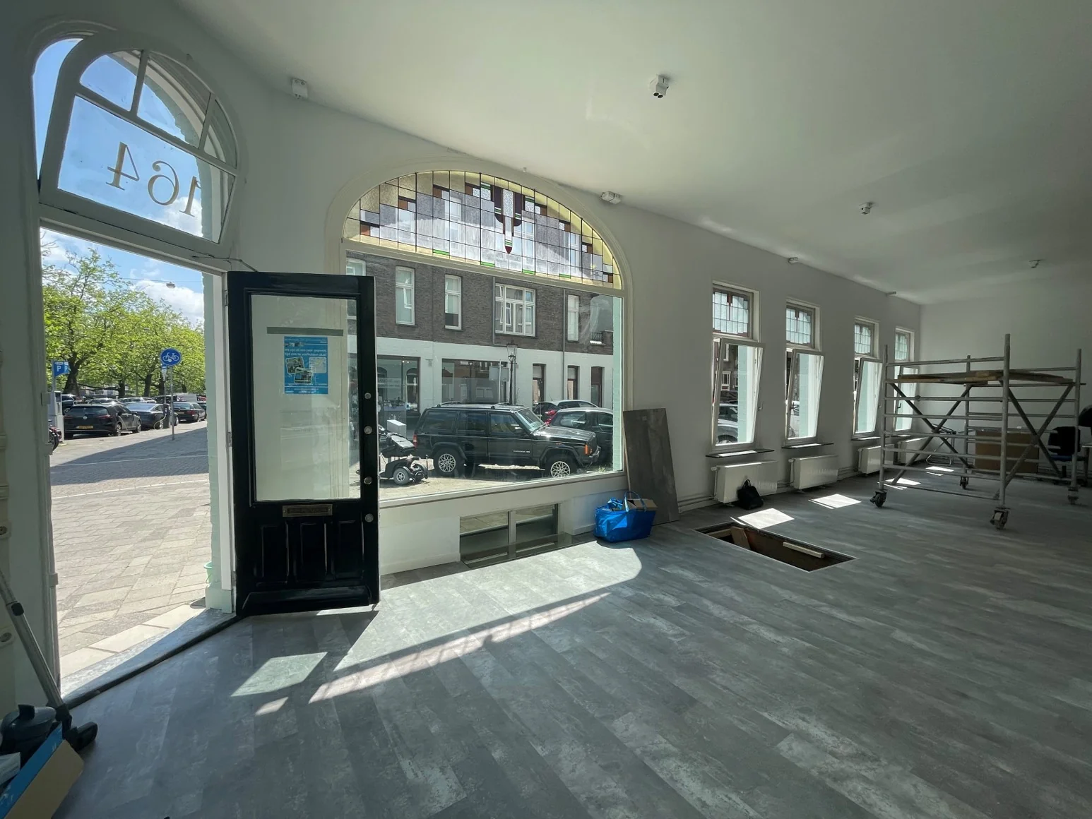 Een lichte ruimte aan de Nassaukade met grote ramen, een openstaande deur en een vloer in aanbouw.