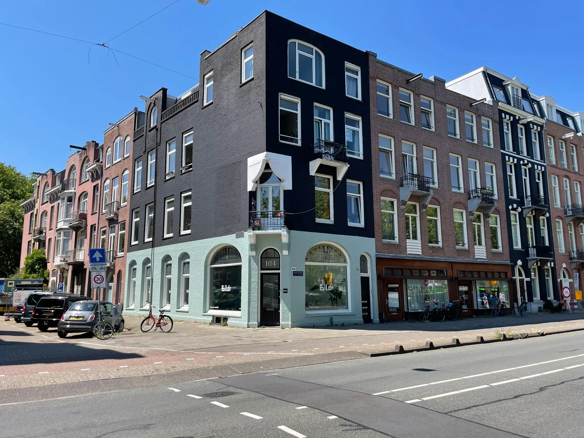 Straatbeeld van de Nassaukade met een hoekpand op nummer 164 met de winkel 'Bildr' op de begane grond.