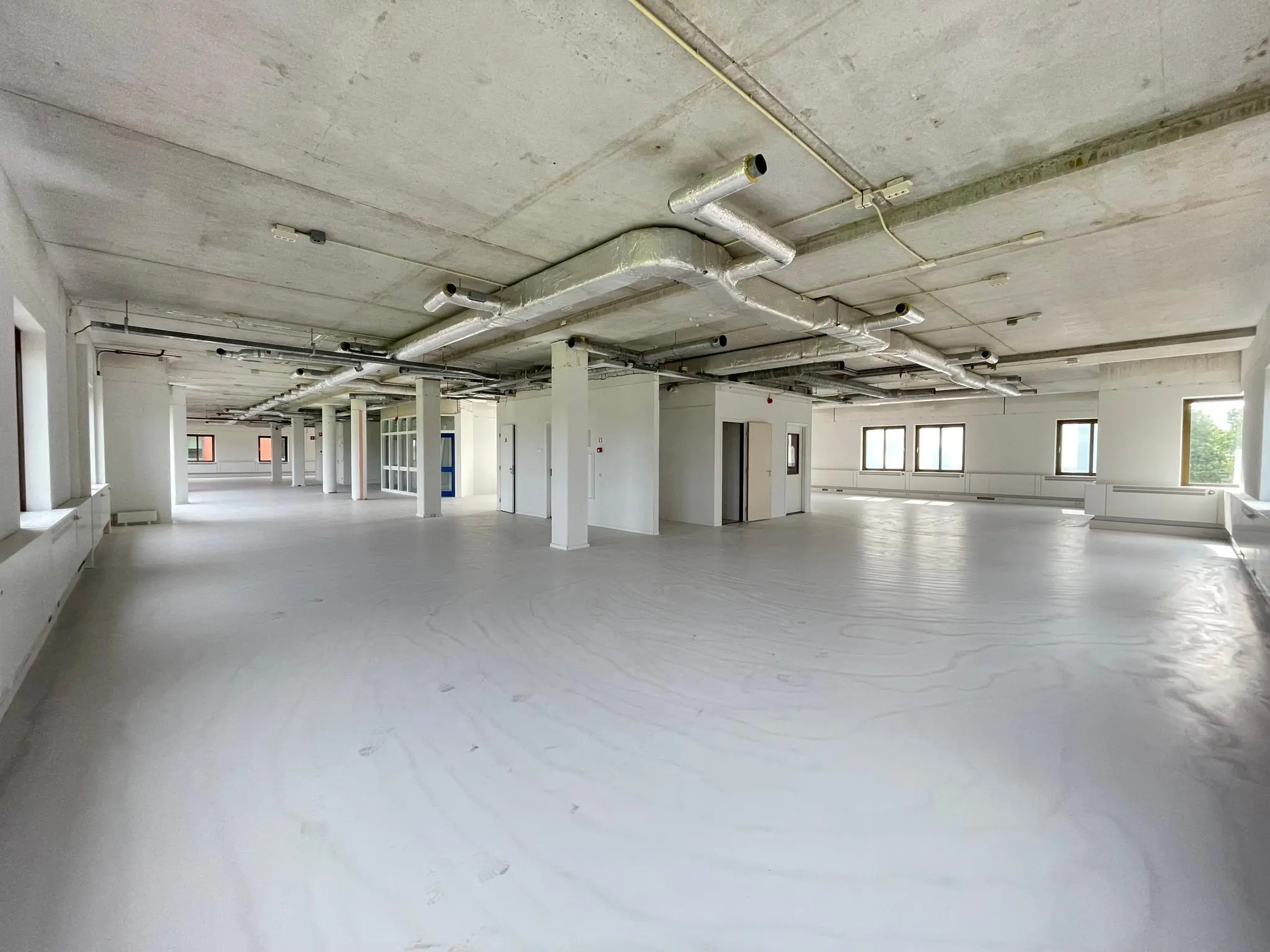 Leeg kantoorpand aan de Lichtenauerlaan met zicht op een afgewerkte vloer en zichtbare plafondleidingen.