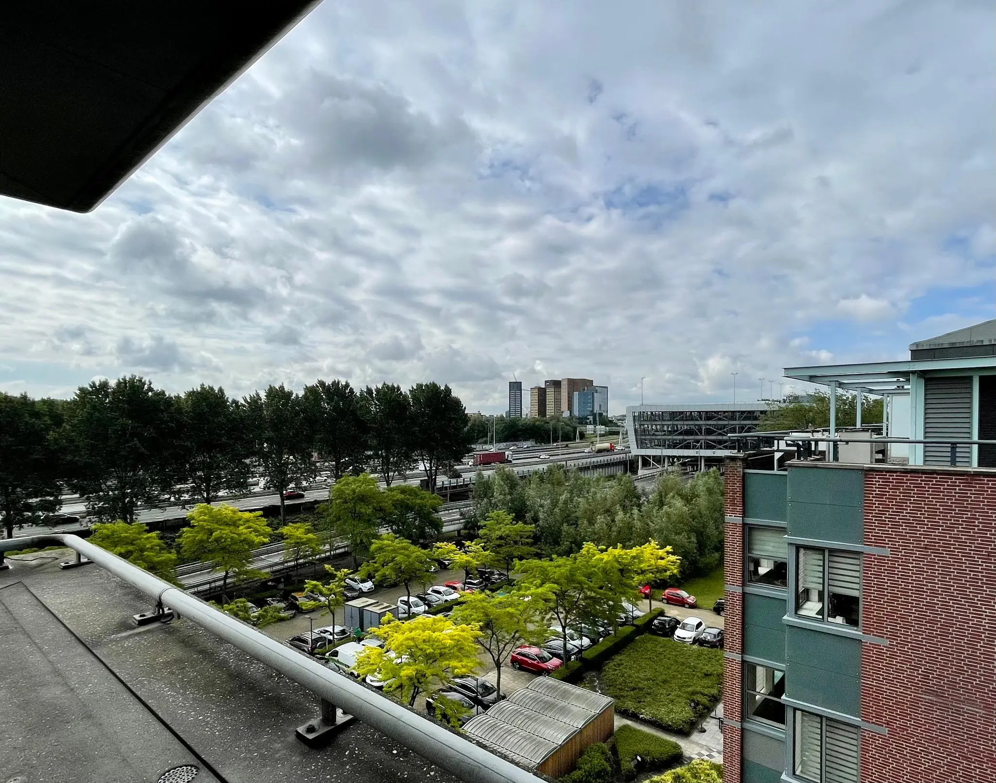 Uitzicht vanaf hoogte op de Lichtenauerlaan in Rotterdam met kantoren, een snelweg en geparkeerde auto's.