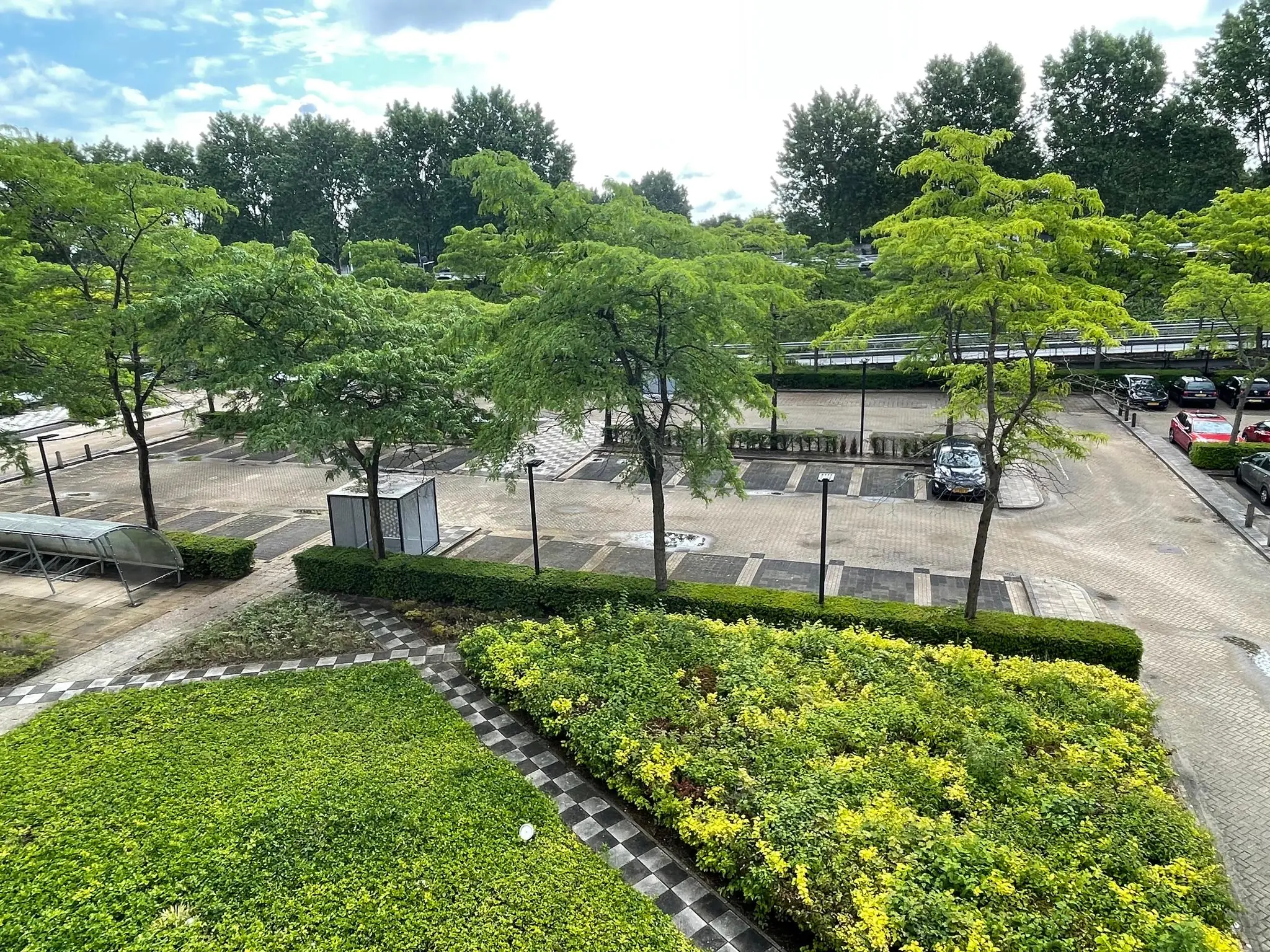 Grote, bijna lege parkeerplaats aan de Lichtenauerlaan, omringd door groene bomen en struiken.