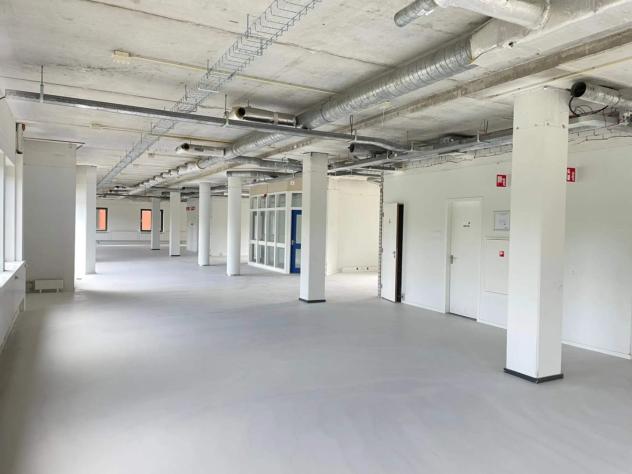 Open kantoorruimte aan de Lichtenauerlaan met zichtbare ventilatiebuizen en witte ondersteuningselementen.