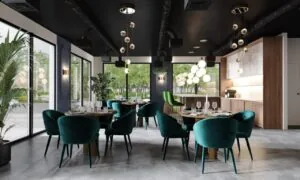 Modern ingericht restaurant aan de Grasweg met groene fluwelen stoelen, ronde tafels en grote ramen met uitzicht op groen.