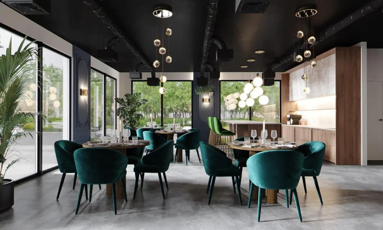 Modern ingericht restaurant aan de Grasweg met groene fluwelen stoelen, ronde tafels en grote ramen met uitzicht op groen.