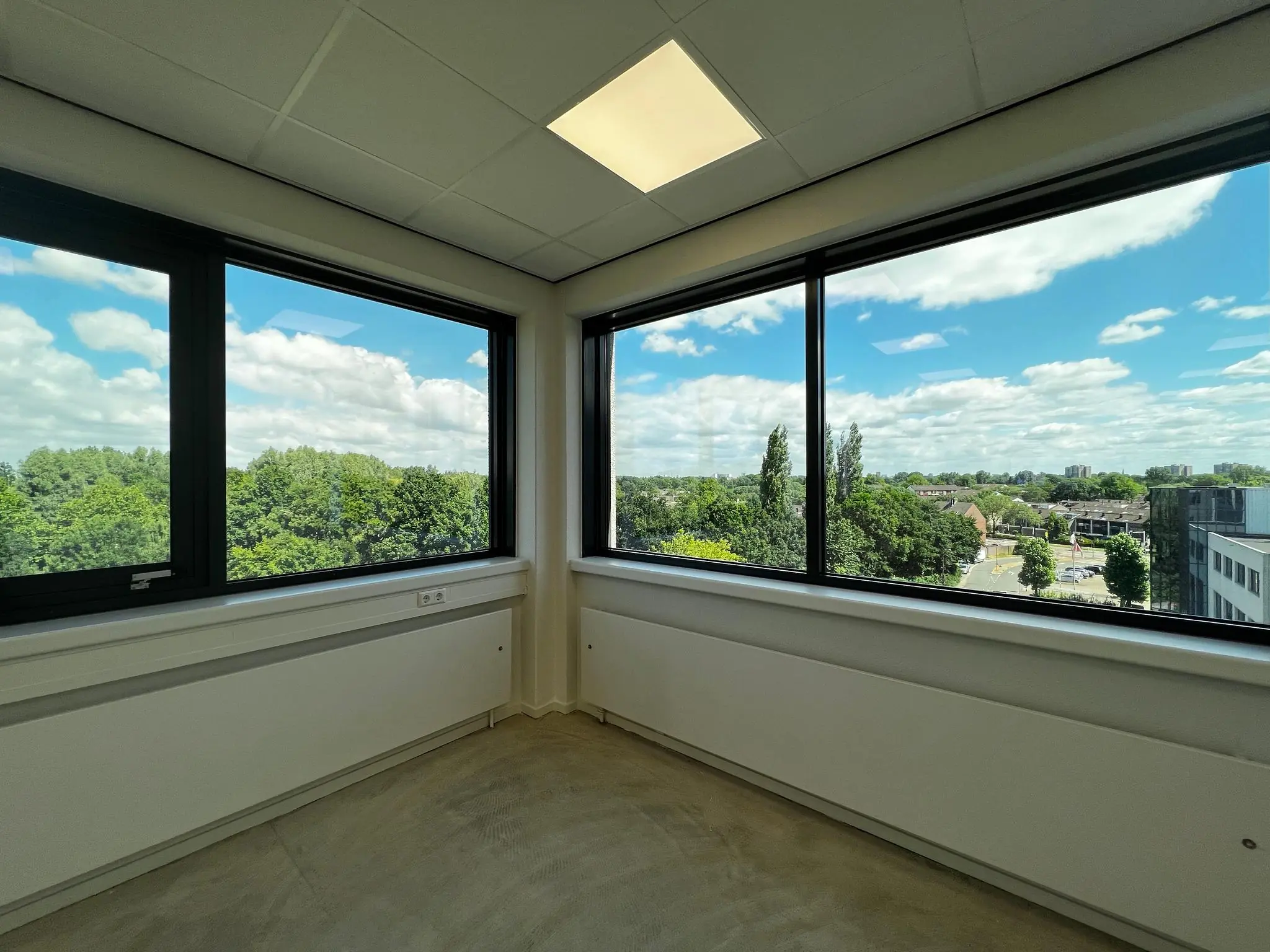Leeg hoekkantoor met grote ramen en uitzicht op groen en stad aan de Nevelgaarde.