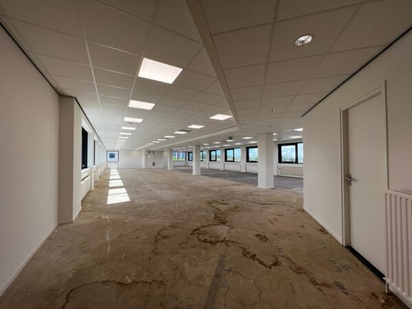 Lege kantoorruimte aan de Nevelgaarde met systeemplafond, grote ramen en deels onafgewerkte vloer.