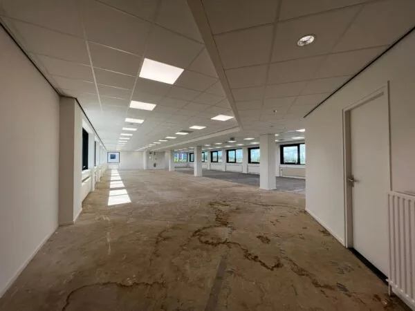 Lege kantoorruimte aan de Nevelgaarde met systeemplafond, grote ramen en deels onafgewerkte vloer.