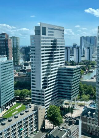 Hoog gebouw Blaak 555 in Rotterdam met op de achtergrond de Erasmusbrug en omliggende moderne architectuur.
