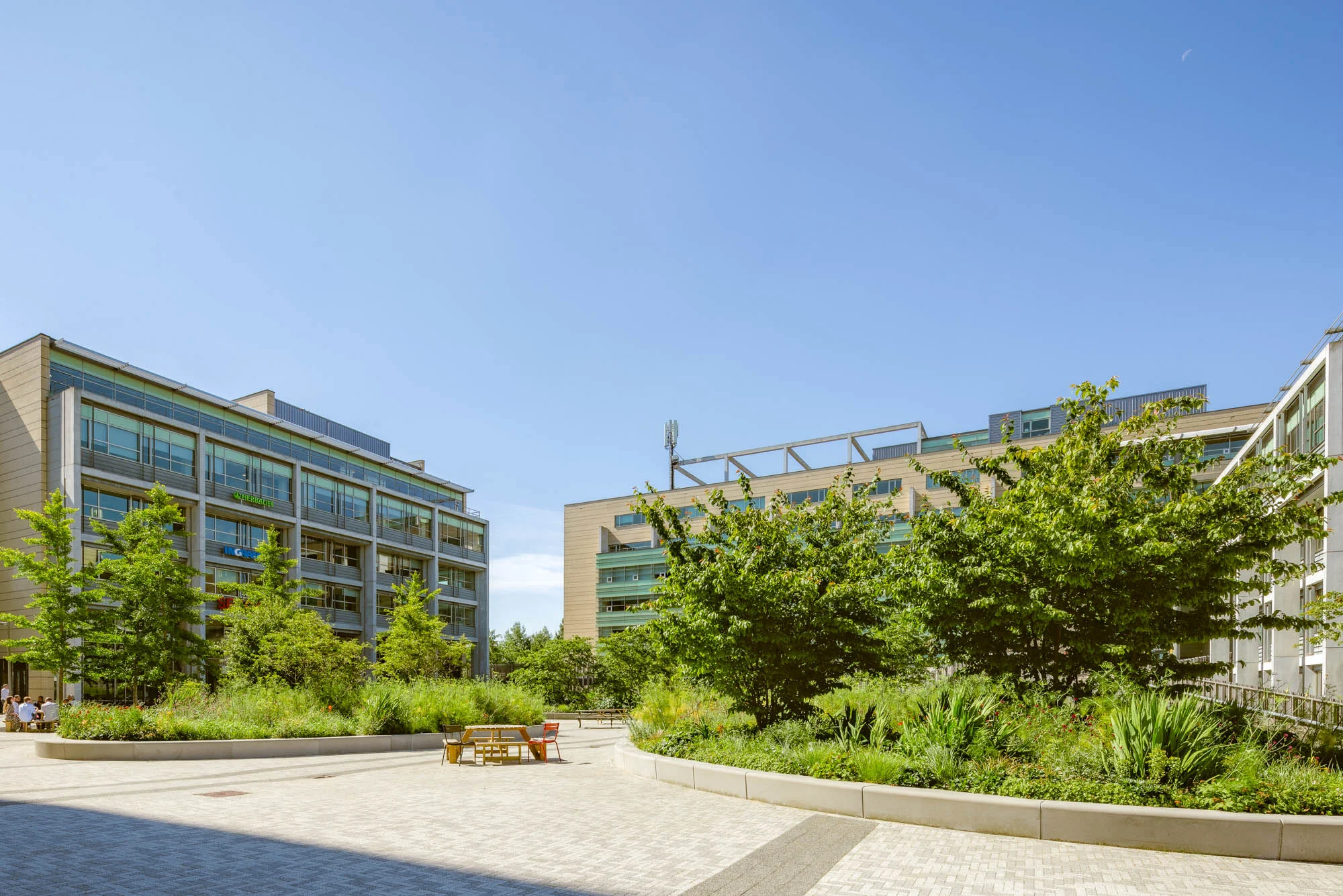 Moderne kantoorgebouwen aan de Papendorpseweg met een groene binnentuin en zitplaatsen onder een heldere blauwe lucht.