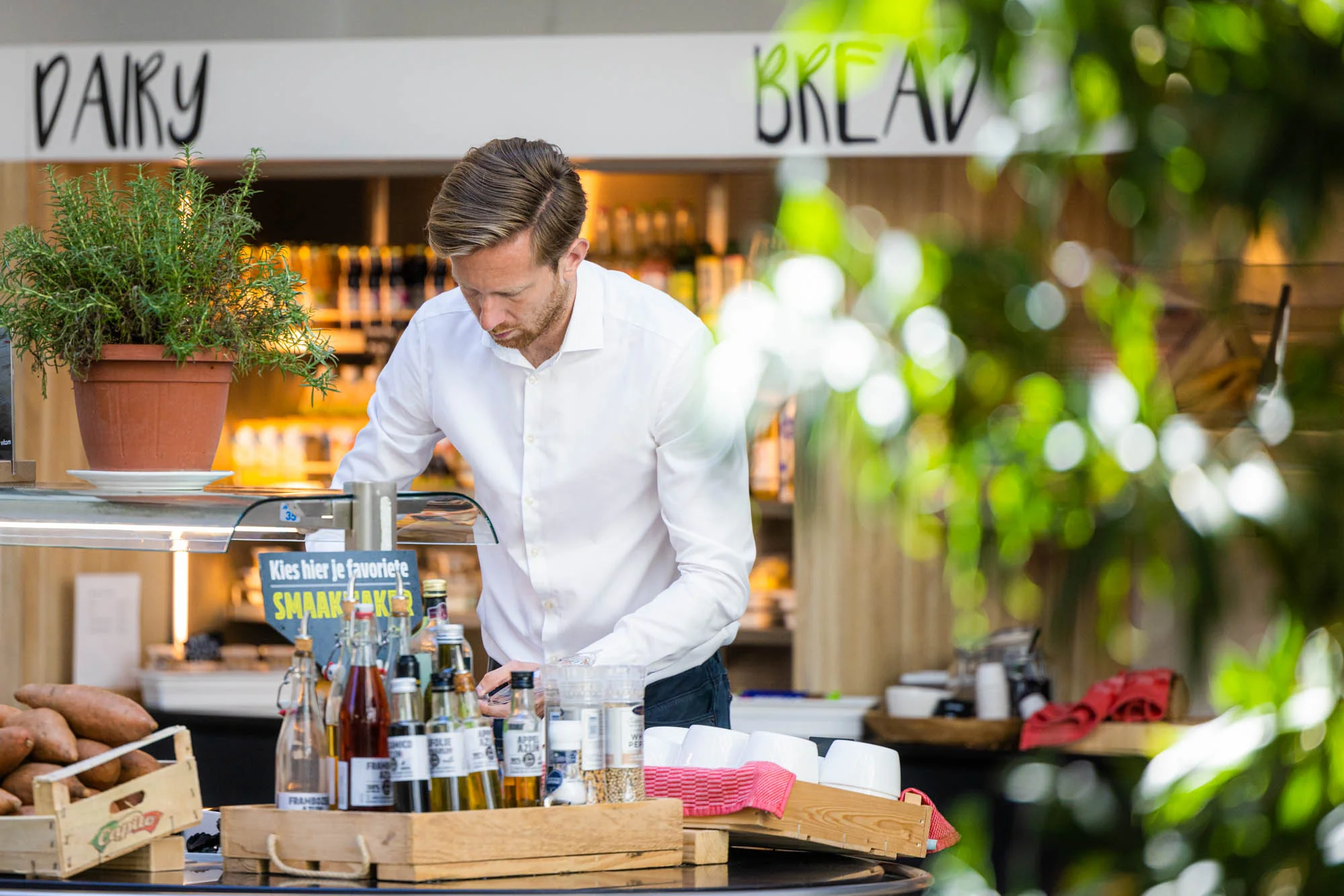 Man in wit overhemd stelt een saladebar samen in een moderne eetruimte aan de Papendorpseweg.