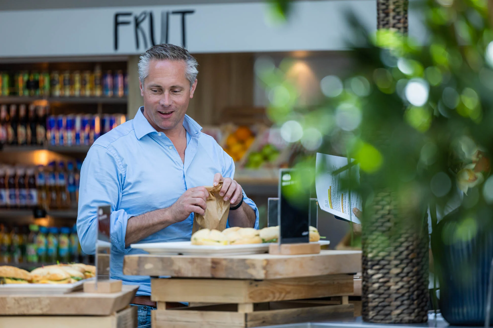Man pakt een broodje bij een lunchbalie in een moderne winkelruimte aan de Papendorpseweg.