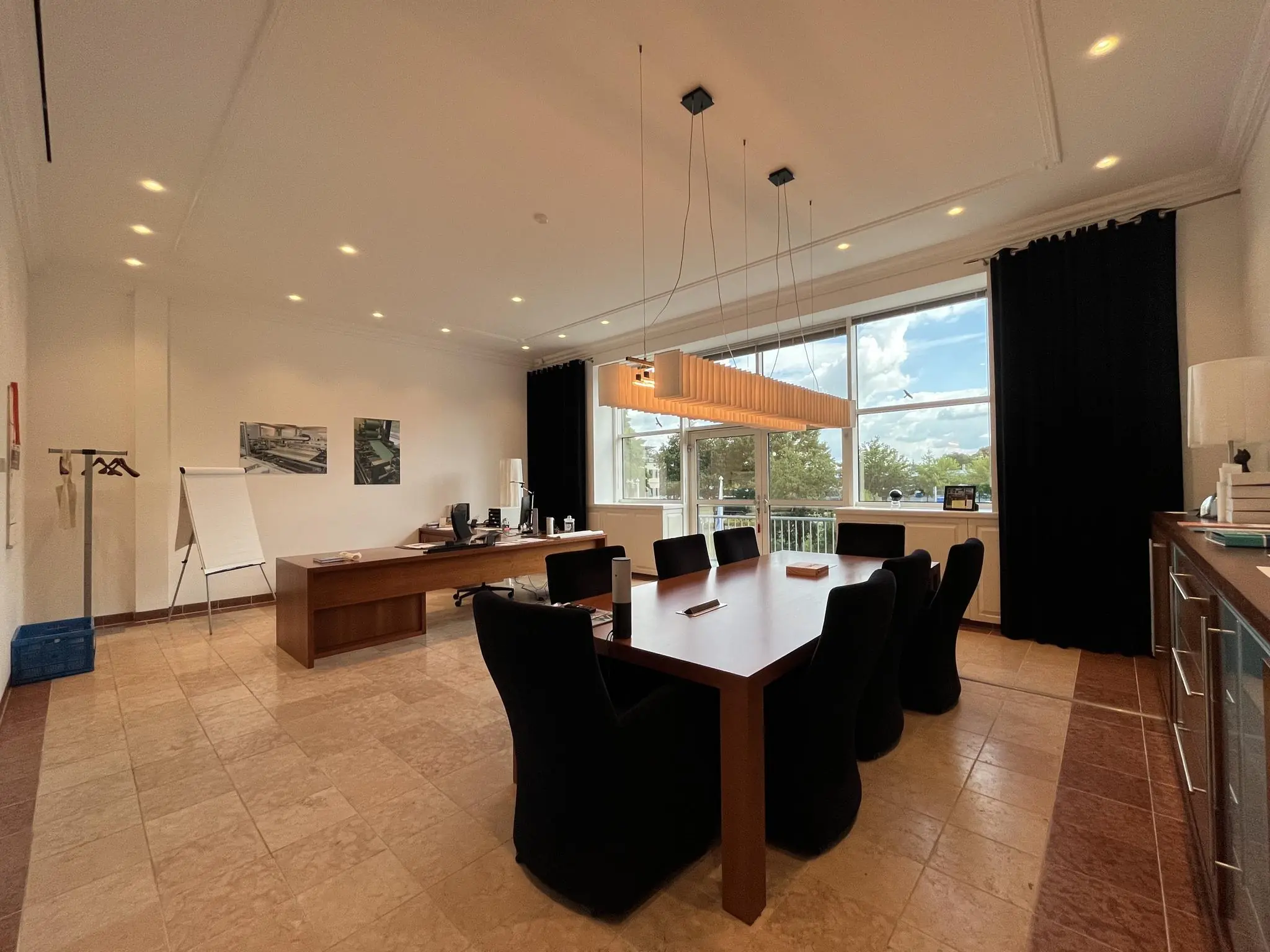 Moderne vergaderruimte aan de Oostergracht met houten vergadertafel, grote ramen en uitzicht op groen.