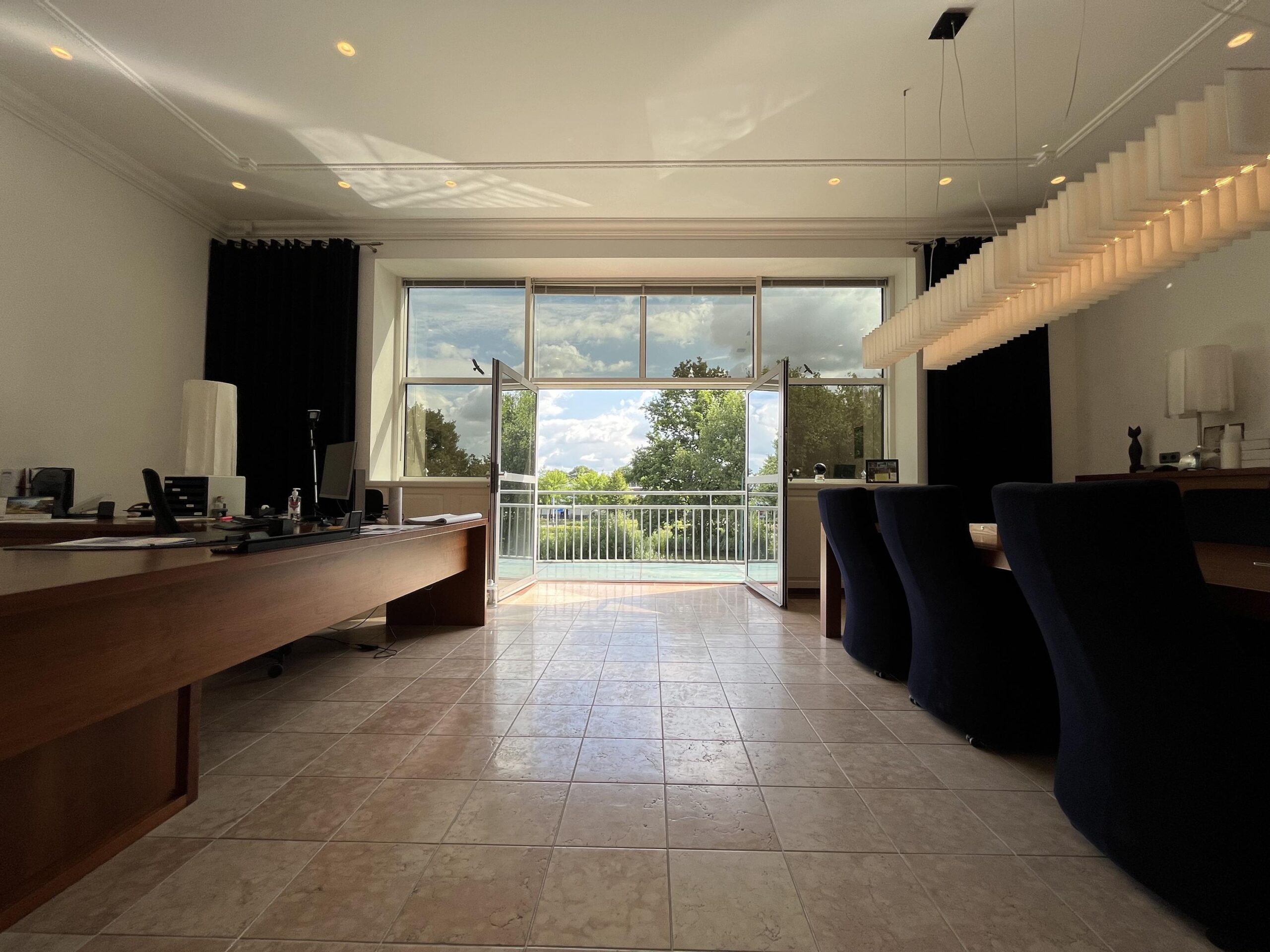 Een modern ingerichte kantoorruimte met een groot raam dat uitzicht biedt op een groene omgeving.