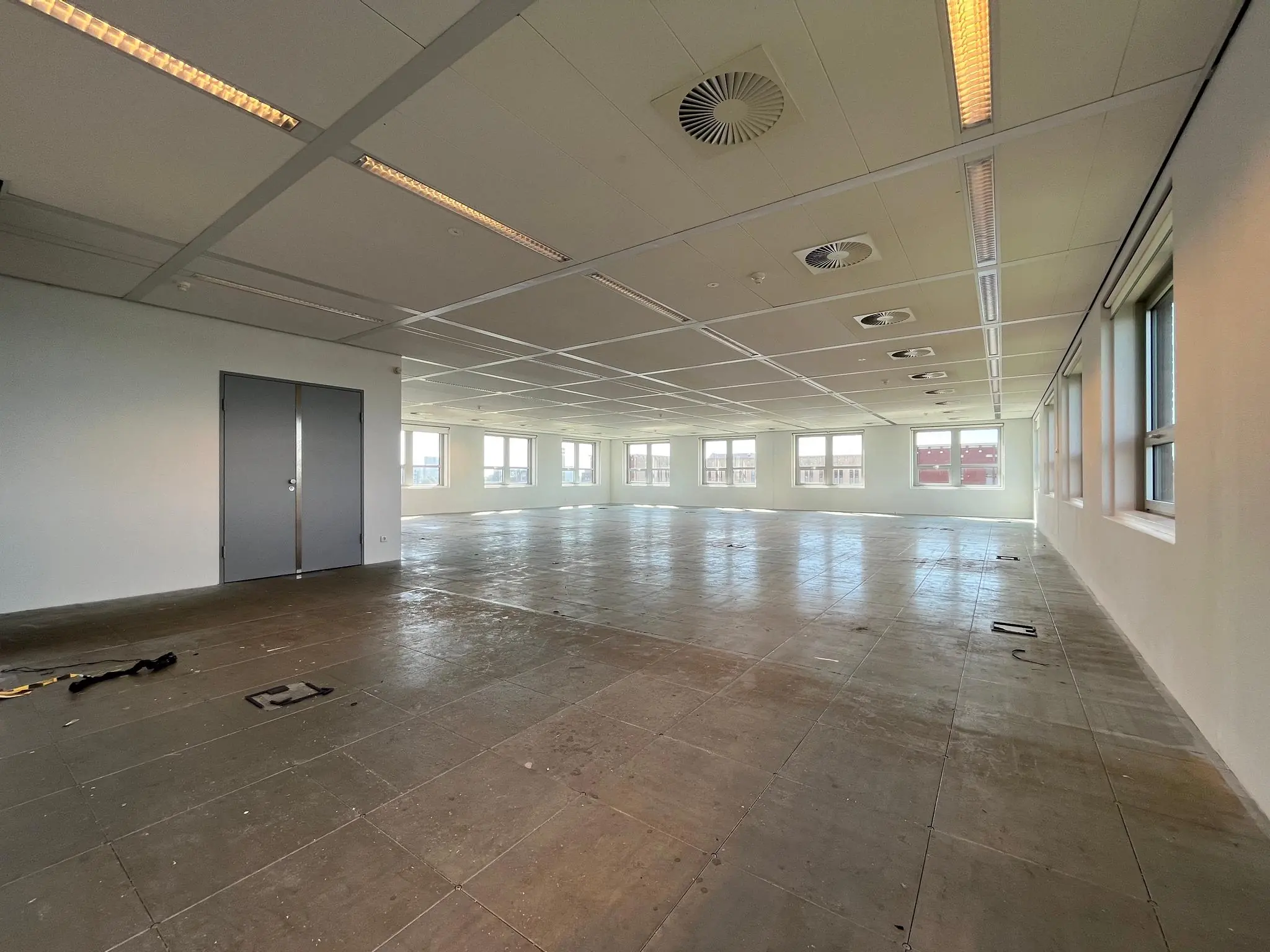 Leegstaand kantoorpand aan de Orteliuslaan met betonnen vloer en grote ramen.