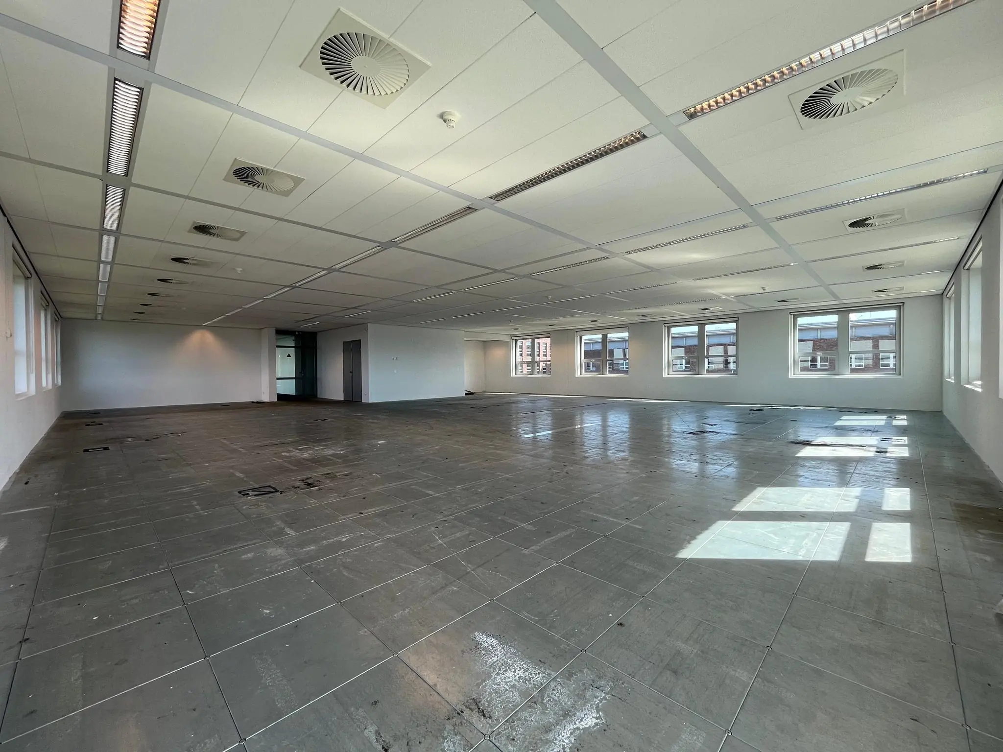 Leeg kantoorpand met systeemplafond en grote ramen aan de Orteliuslaan.