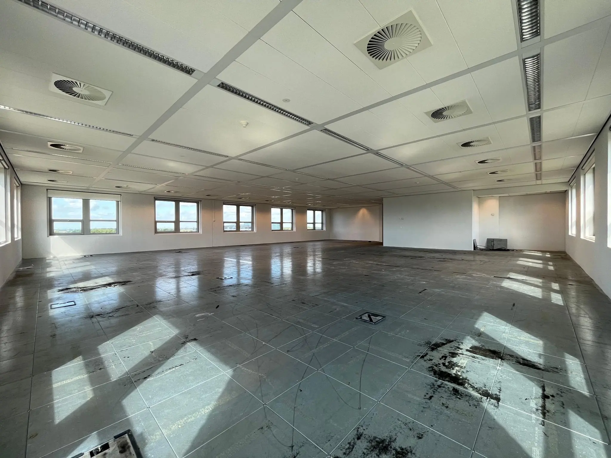 Leegstaande kantoorruimte met systeemplafond en grote ramen aan de Orteliuslaan.