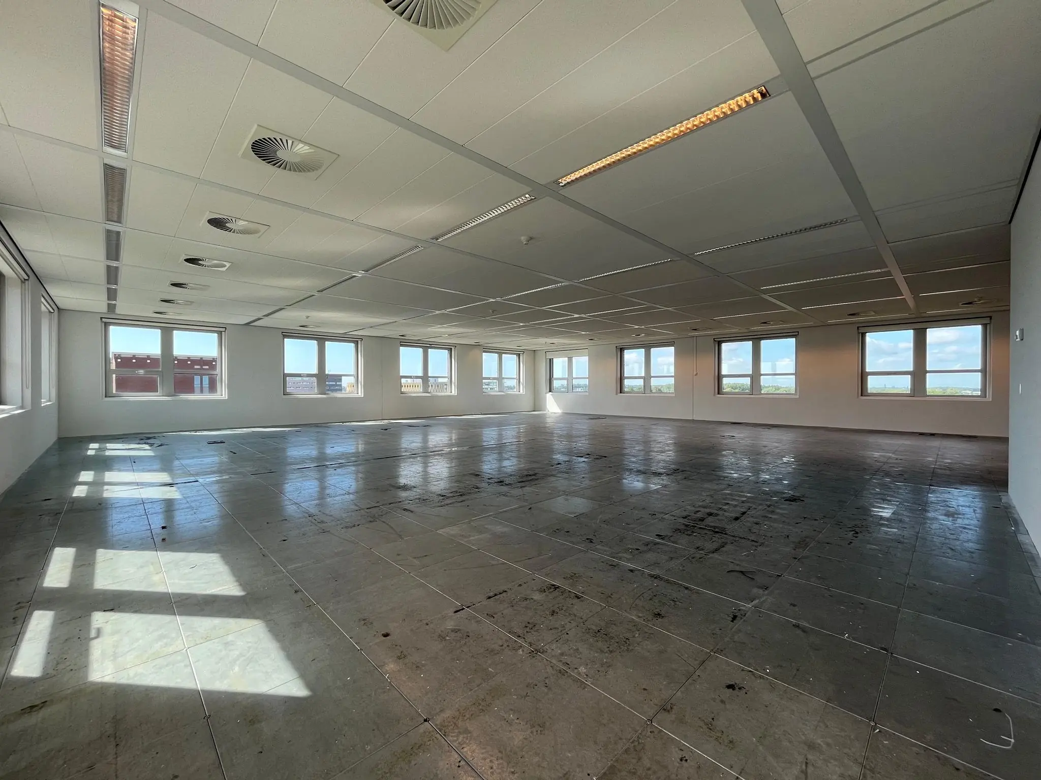 Leeg kantoorpand aan de Orteliuslaan met grote ramen en systeemplafond.