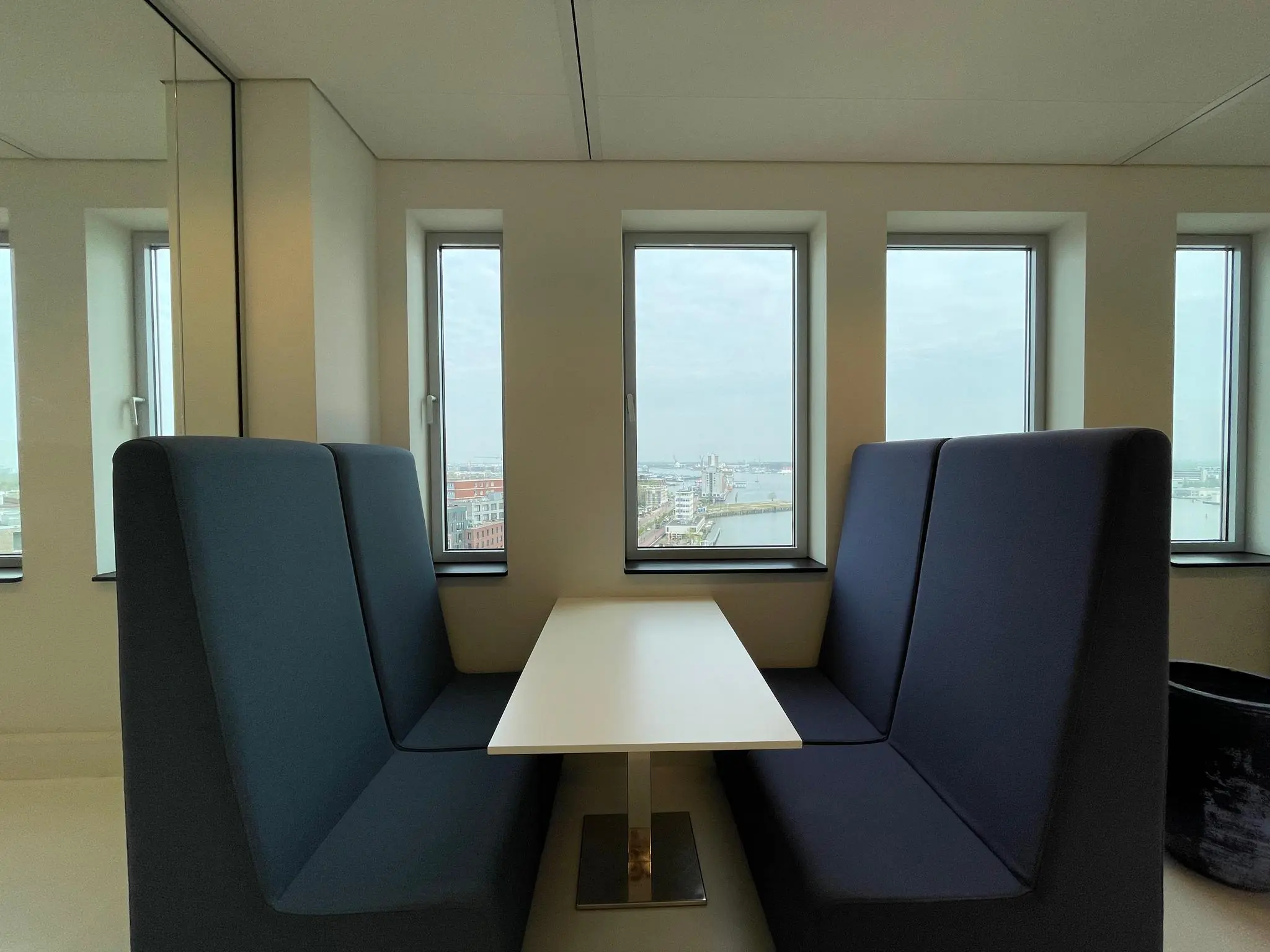 Zitje met hoge banken en tafel bij raam met uitzicht op het IJdok in Amsterdam.