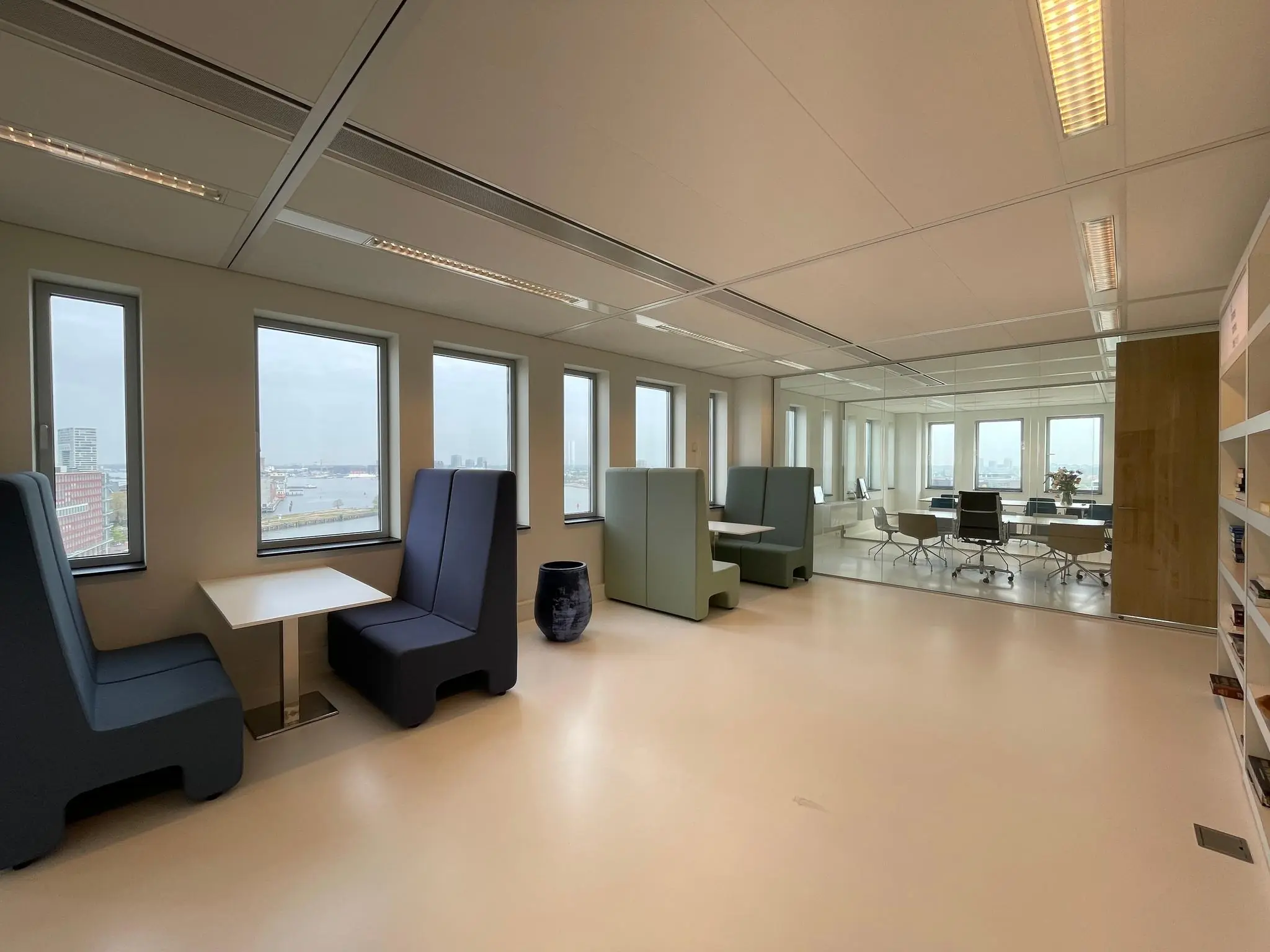 Moderne kantoorruimte aan het IJdok met zitjes bij het raam en uitzicht op het water.