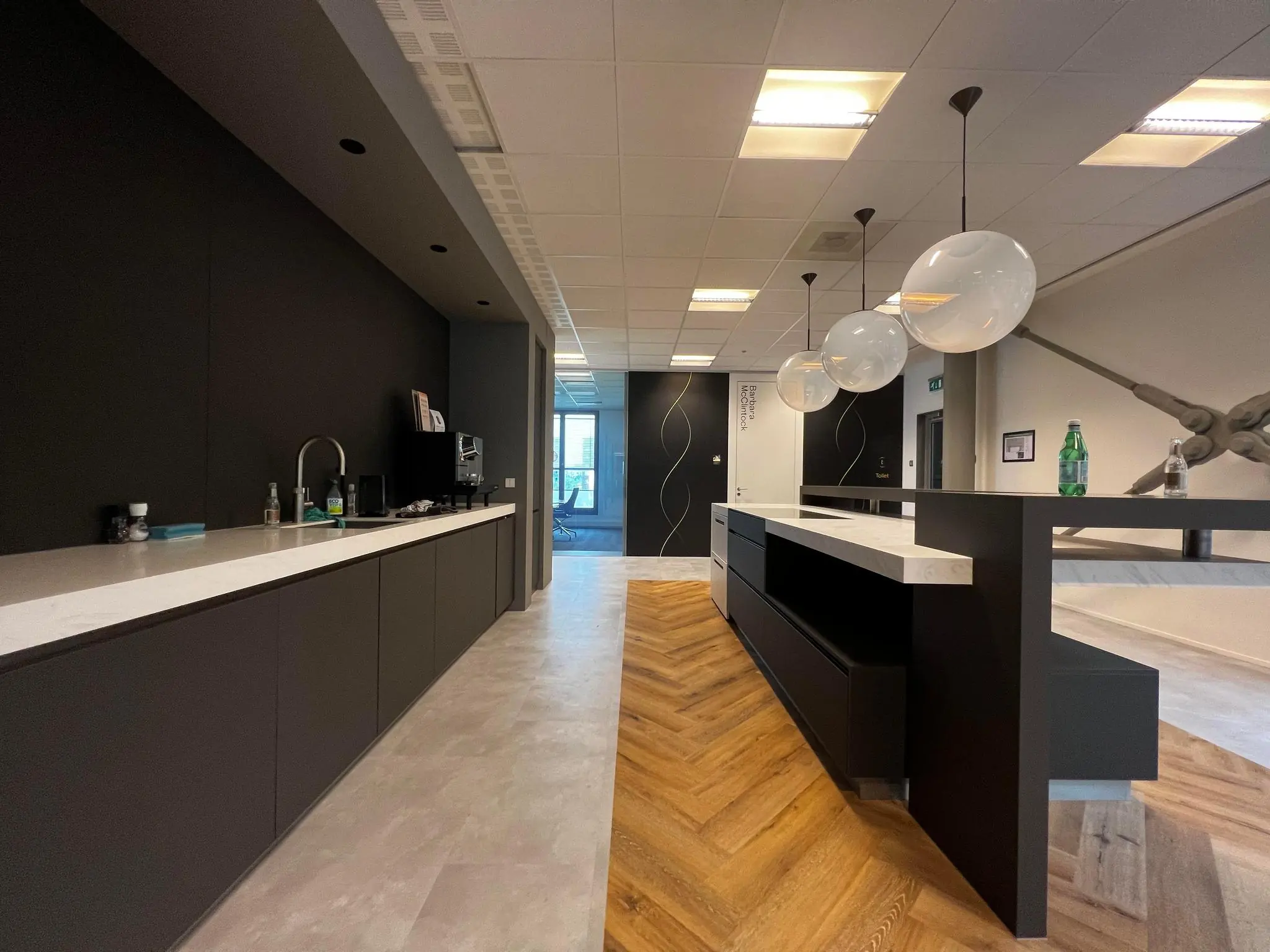 Moderne kantoorruimte aan de Hondiuslaan met een strakke kitchenette, ontvangstbalie en designverlichting.