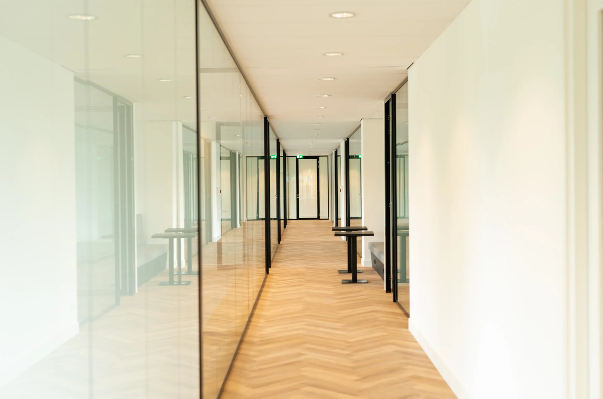Lichte en moderne kantoorruimte aan de Europalaan met glazen wanden en houten visgraatvloer.