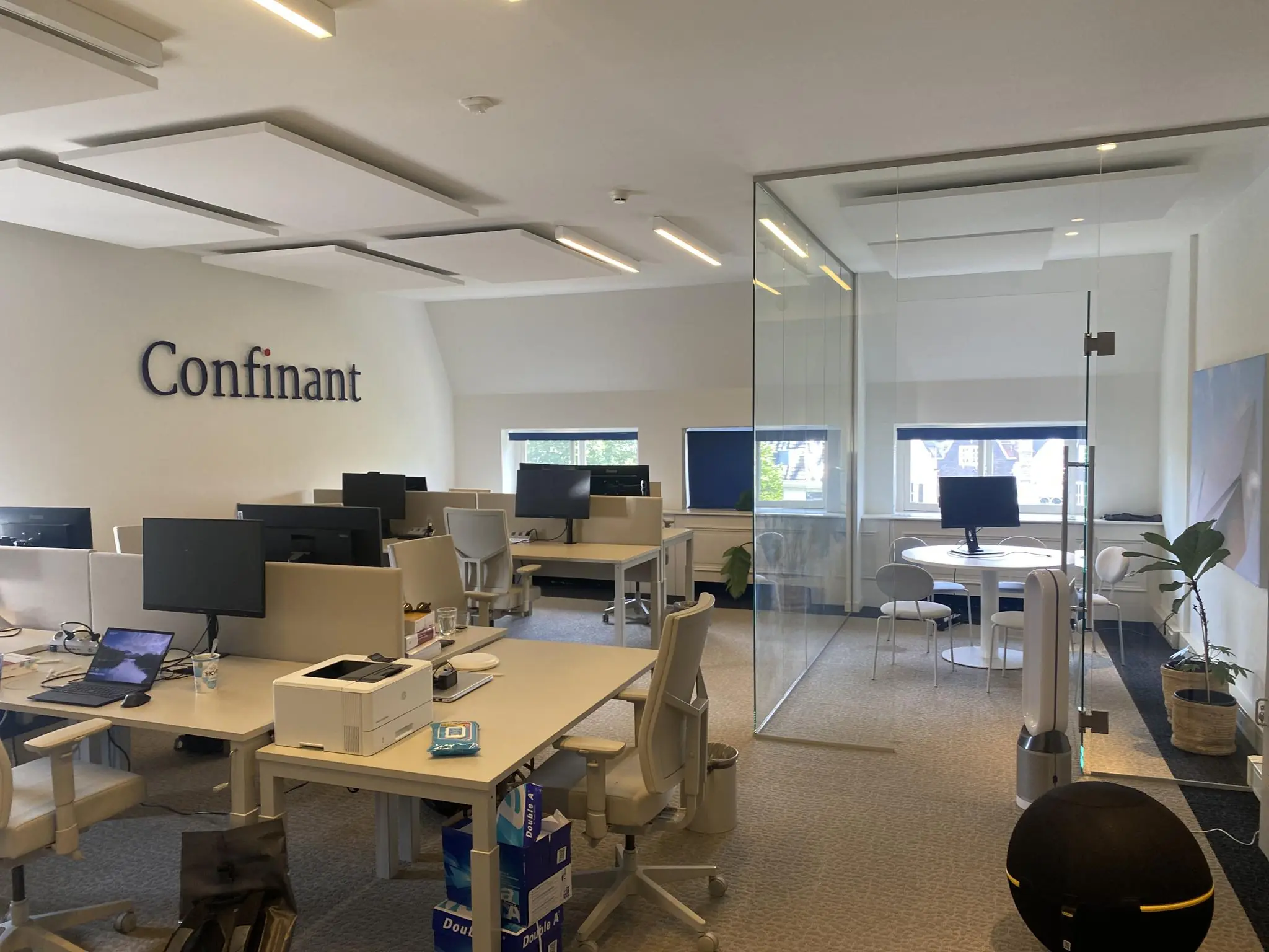 Moderne kantoorruimte van Confinant aan de Herengracht met werkplekken, computers en een glazen vergaderruimte.