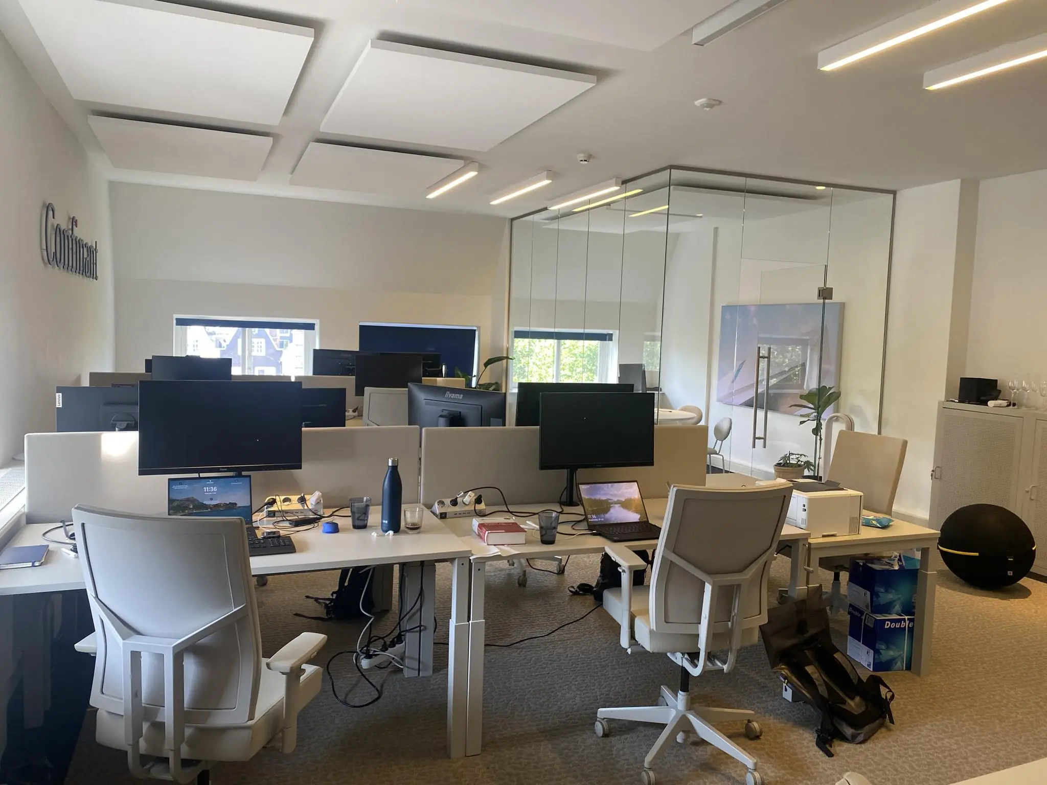 Moderne kantoortuin aan de Herengracht met bureaus, beeldschermen en glazen vergaderruimte.