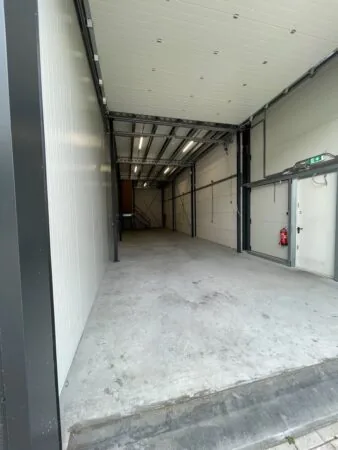 Lege bedrijfsruimte aan de Aalsmeerderweg met betonnen vloer en metalen constructie.