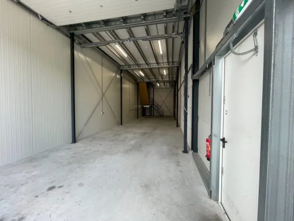 Lege bedrijfsruimte aan de Aalsmeerderweg met betonnen vloer, metalen constructie en trap naar boven.