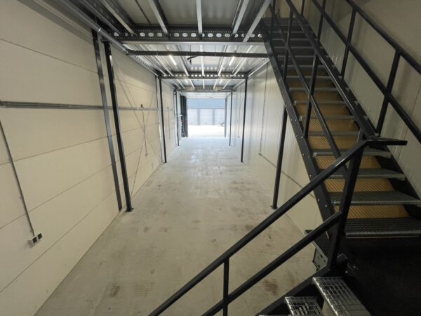 Binnenaanzicht van een lege bedrijfsruimte aan de Aalsmeerderweg met een metalen trap en betonnen vloer.