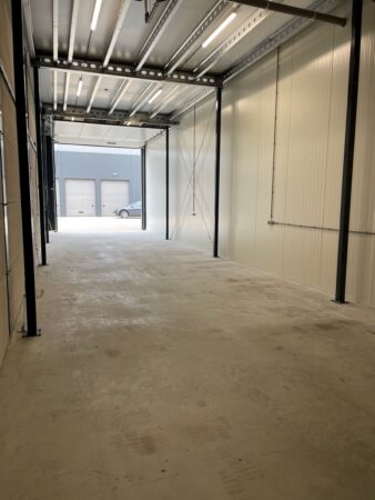Lege bedrijfs- of opslagruimte aan de Aalsmeerderweg met betonnen vloer en open schuifdeur naar buiten.