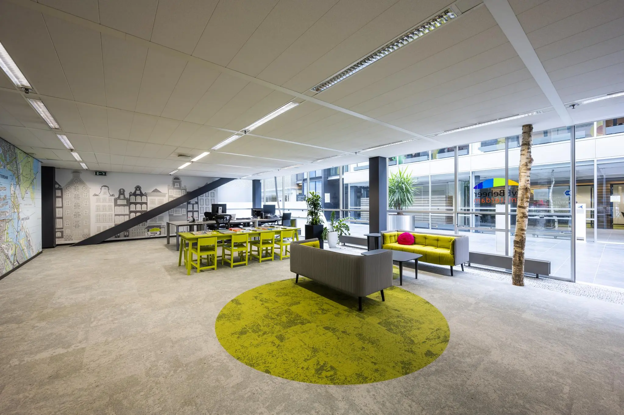 Moderne kantoorruimte aan de Jacob Bontiusplaats met open werkplekken, gele zitmeubels en grote ramen met uitzicht op een binnenplaats.