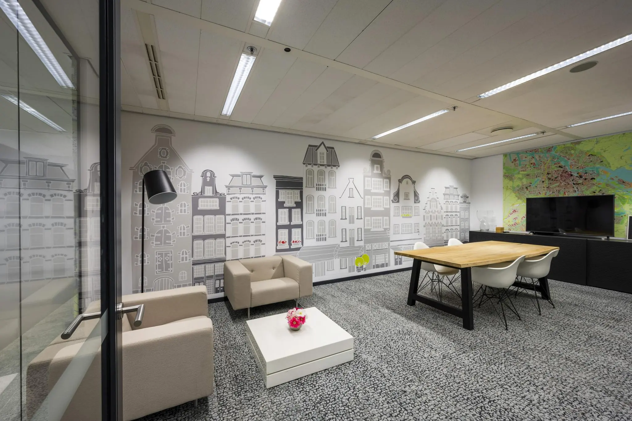Moderne vergaderruimte aan de Jacob Bontiusplaats met een muurillustratie van Amsterdamse gevels en een grote kaart van de stad.