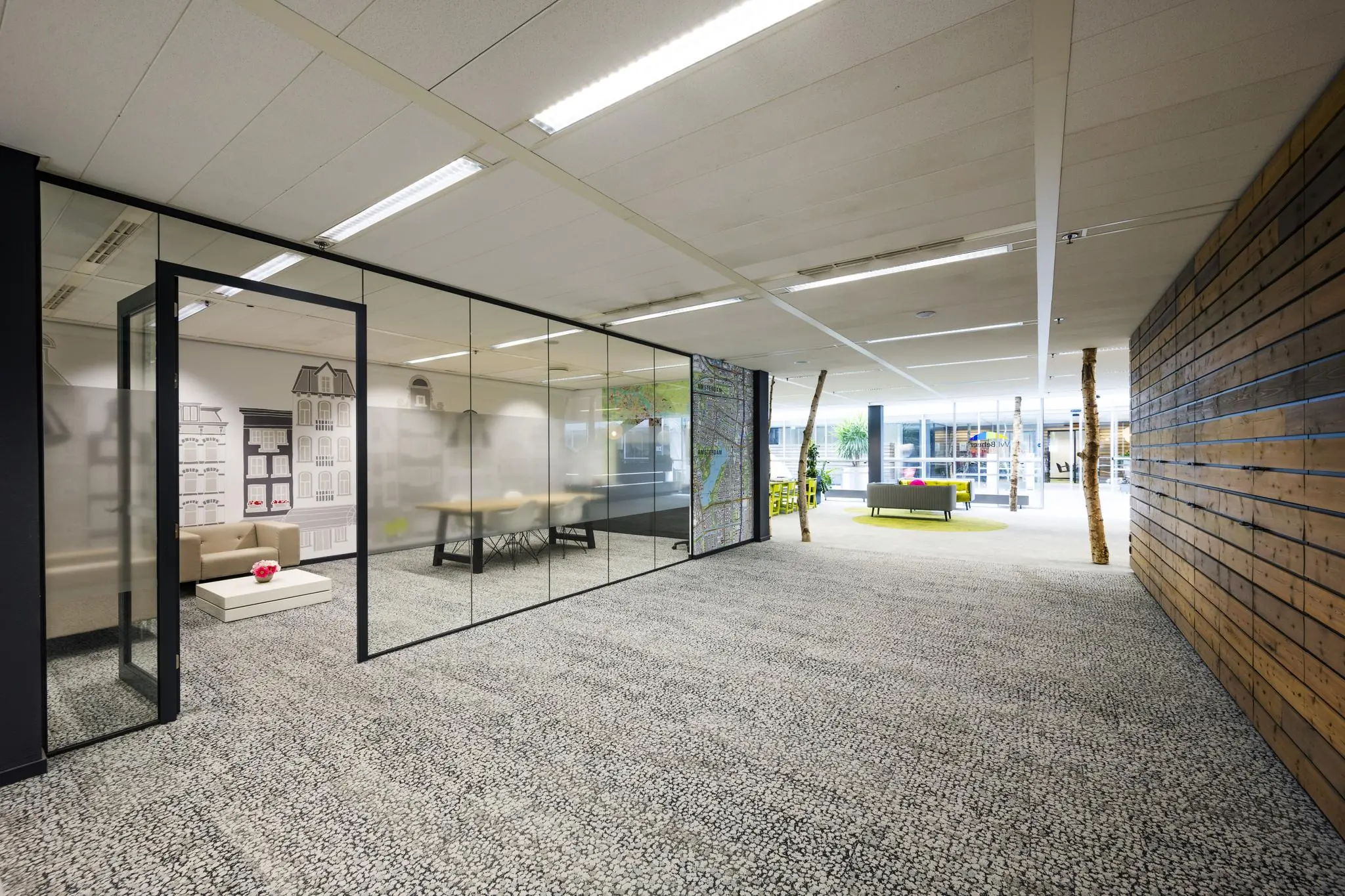 Modern kantoorpand aan de Jacob Bontiusplaats met glazen vergaderruimte, loungehoek en houten accenten.