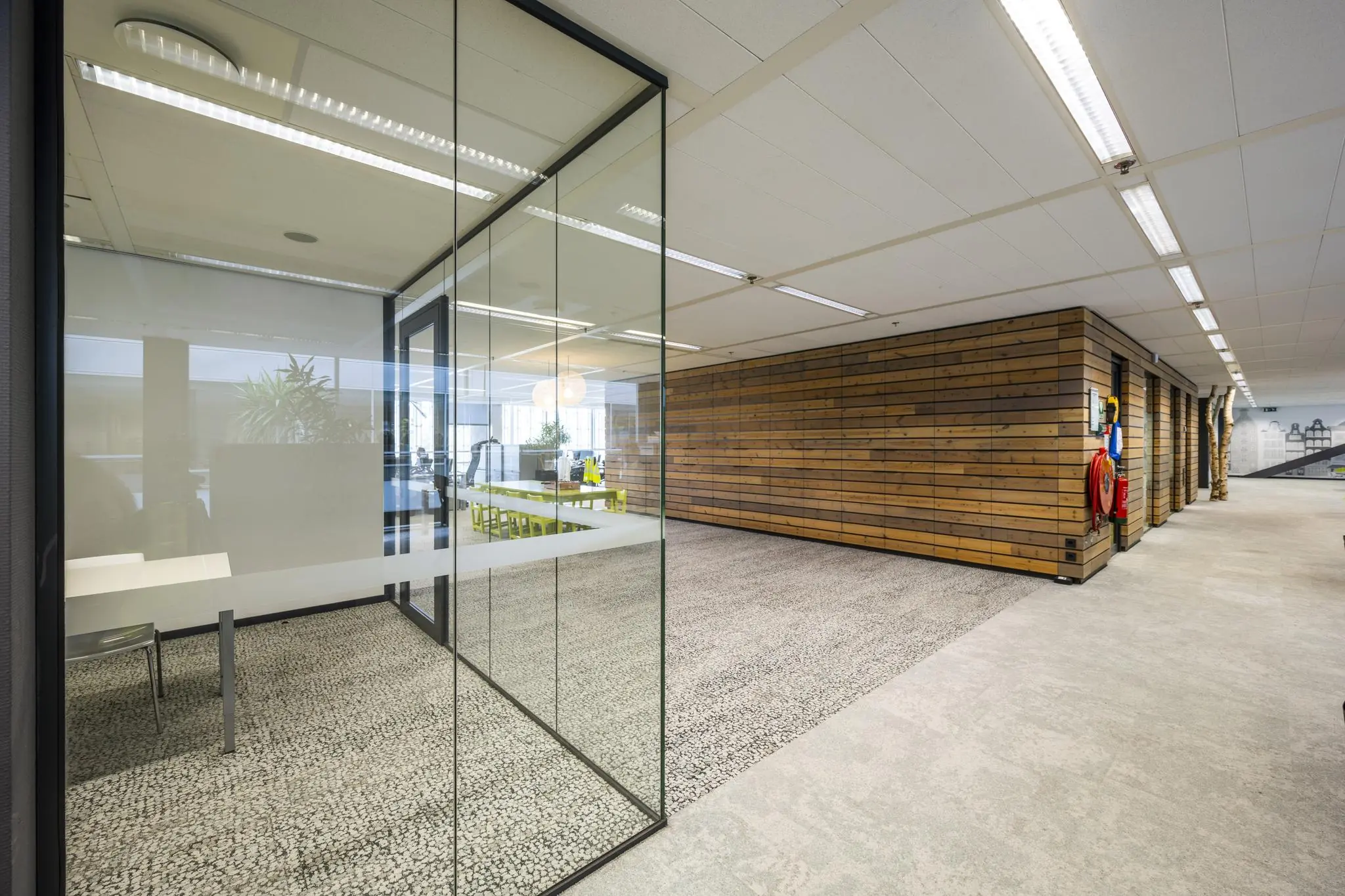 Modern kantoorinterieur aan de Jacob Bontiusplaats met glazen vergaderruimte en houten wandbekleding.