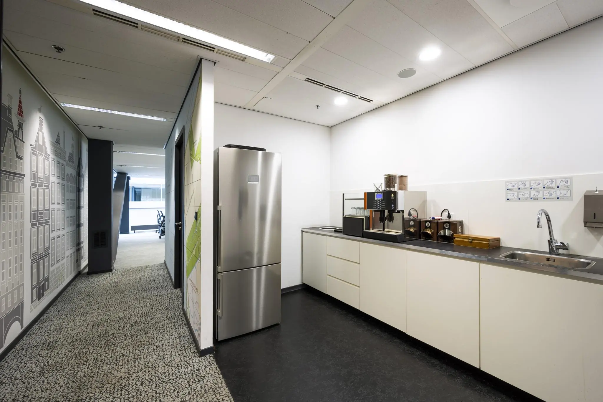 Moderne kantoorkeuken aan de Jacob Bontiusplaats met koffieautomaat, spoelbak en rvs-koelkast.