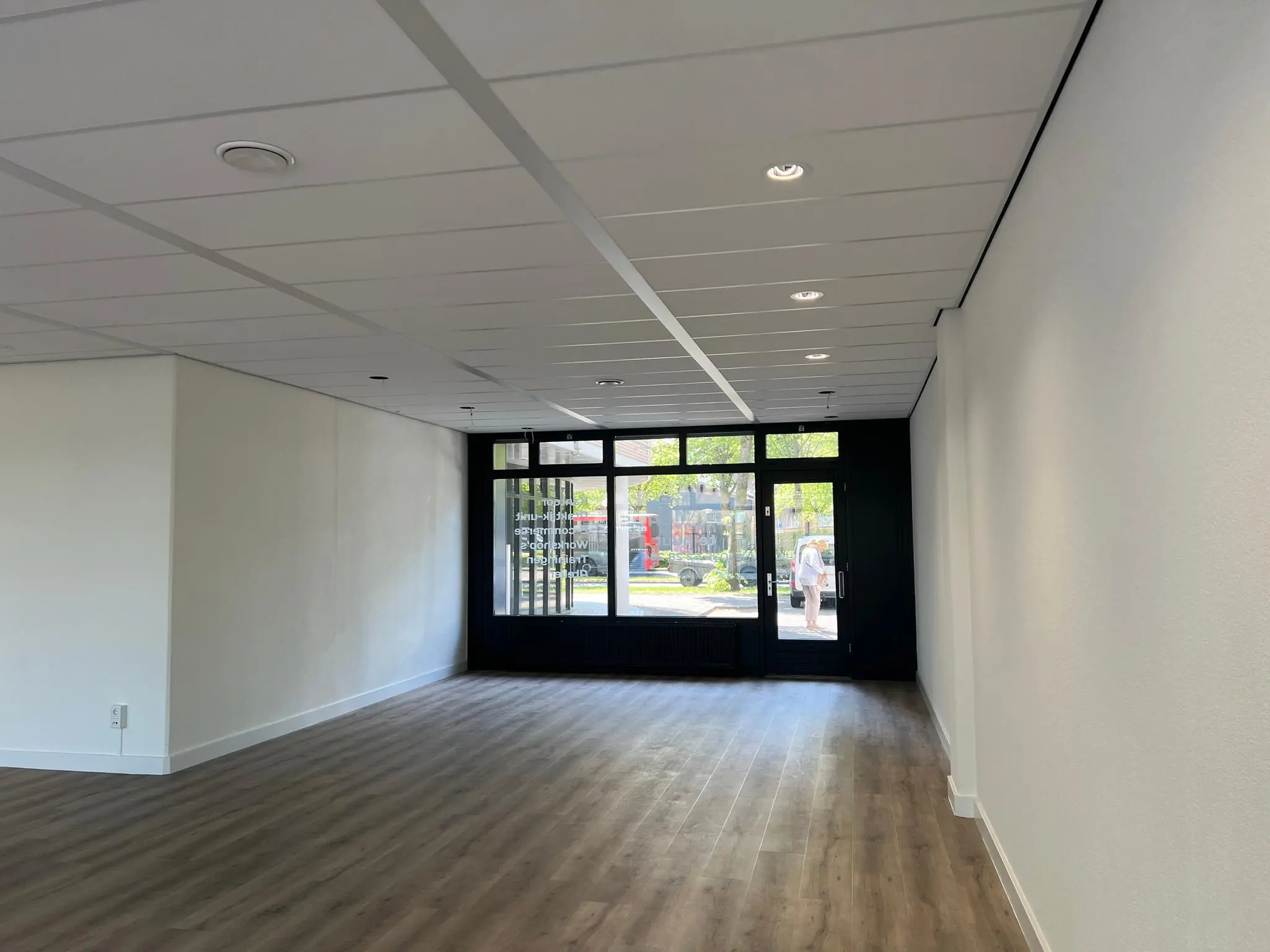 Leeg winkel- of kantoorpand aan de Huizermaatweg met houten vloer en grote glazen pui.