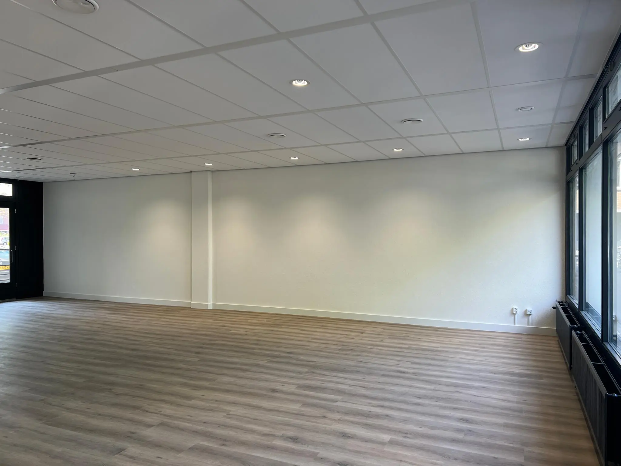 Leeg kantoorpand aan de Huizermaatweg met lichtgrijze muren, systeemplafond en grote ramen.