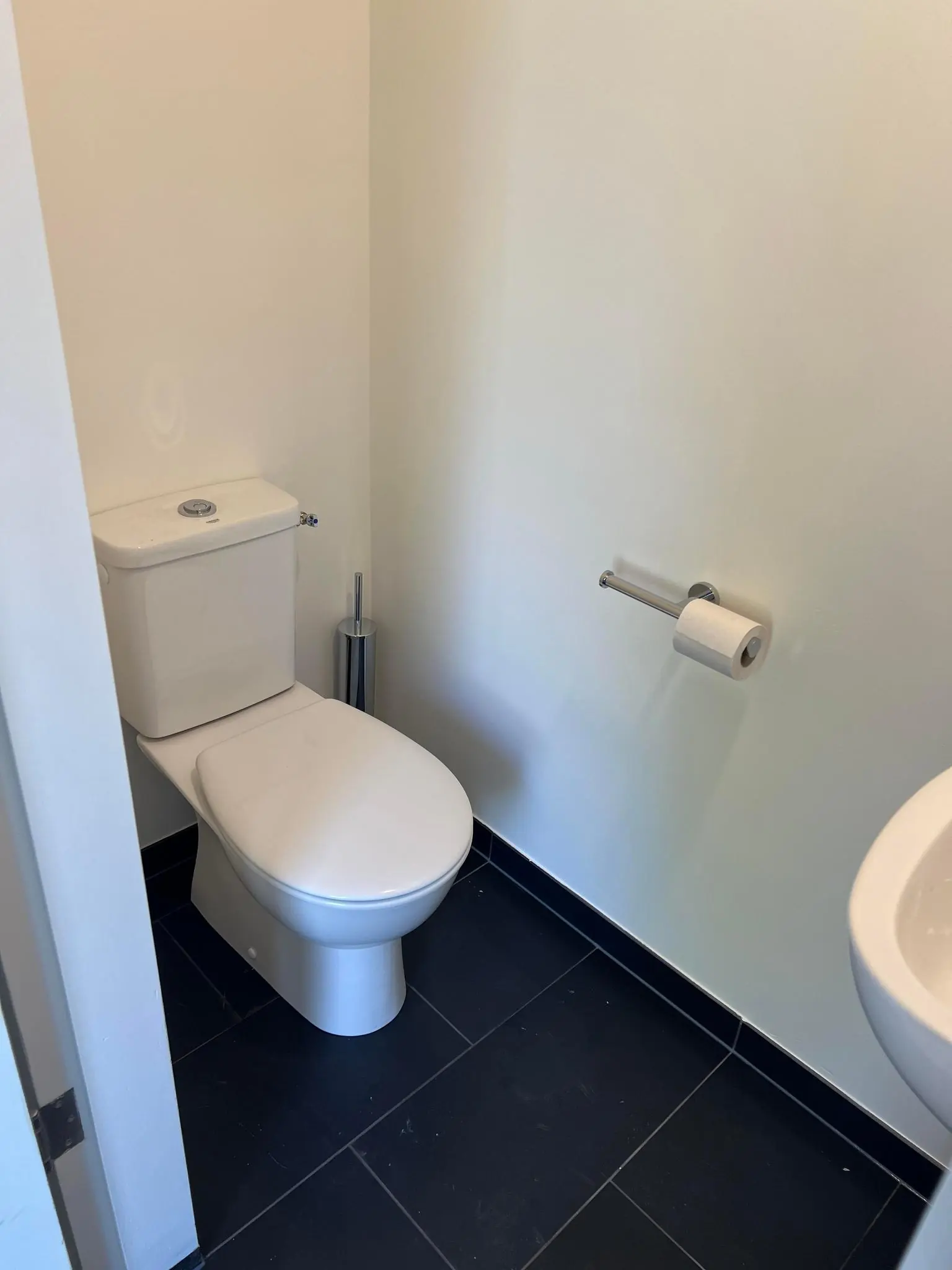 Een modern, minimalistisch toilet met zwarte vloertegels en witte muren aan de Huizermaatweg.